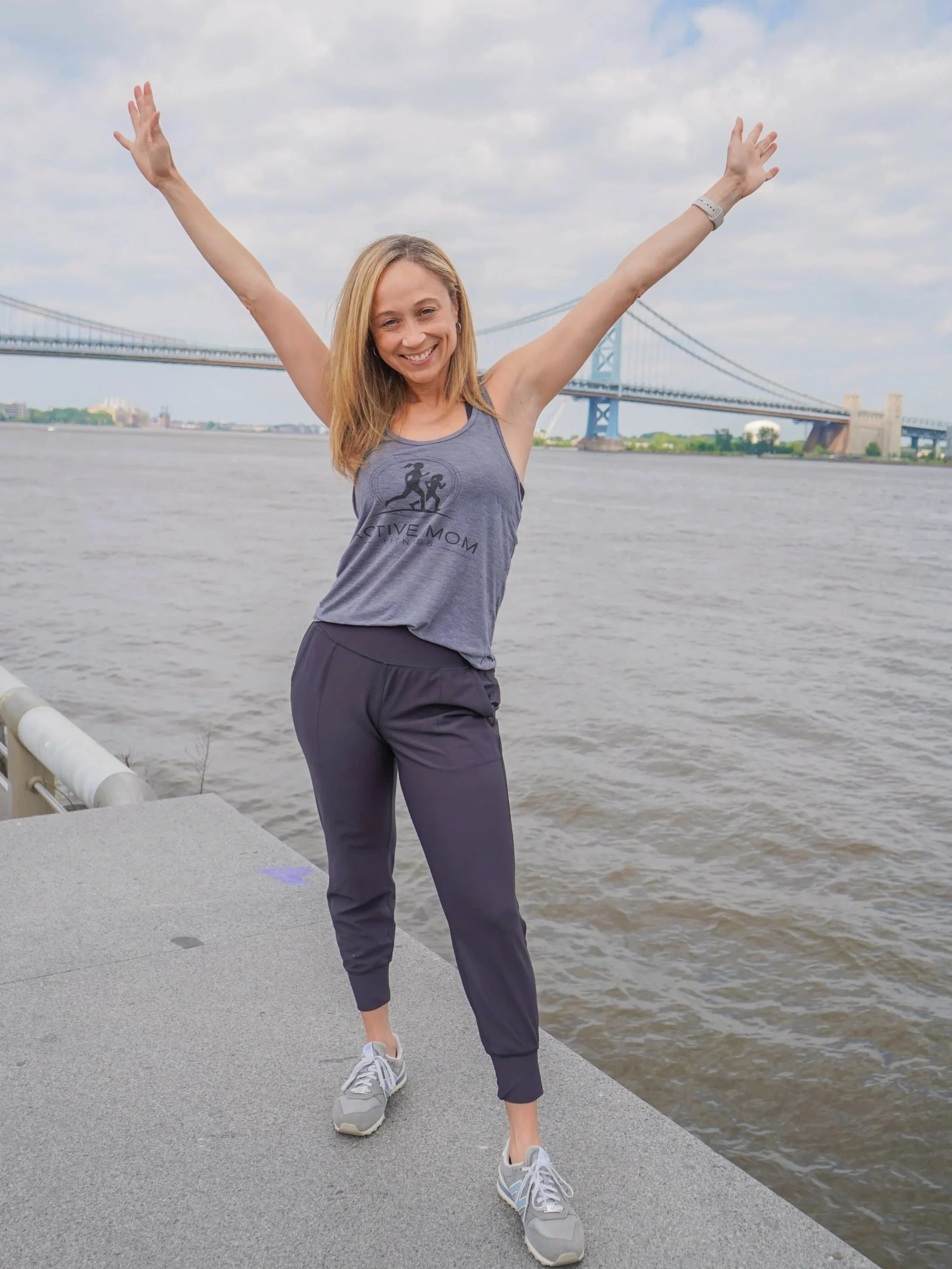 Ashley Reid with her hands up standing by the river