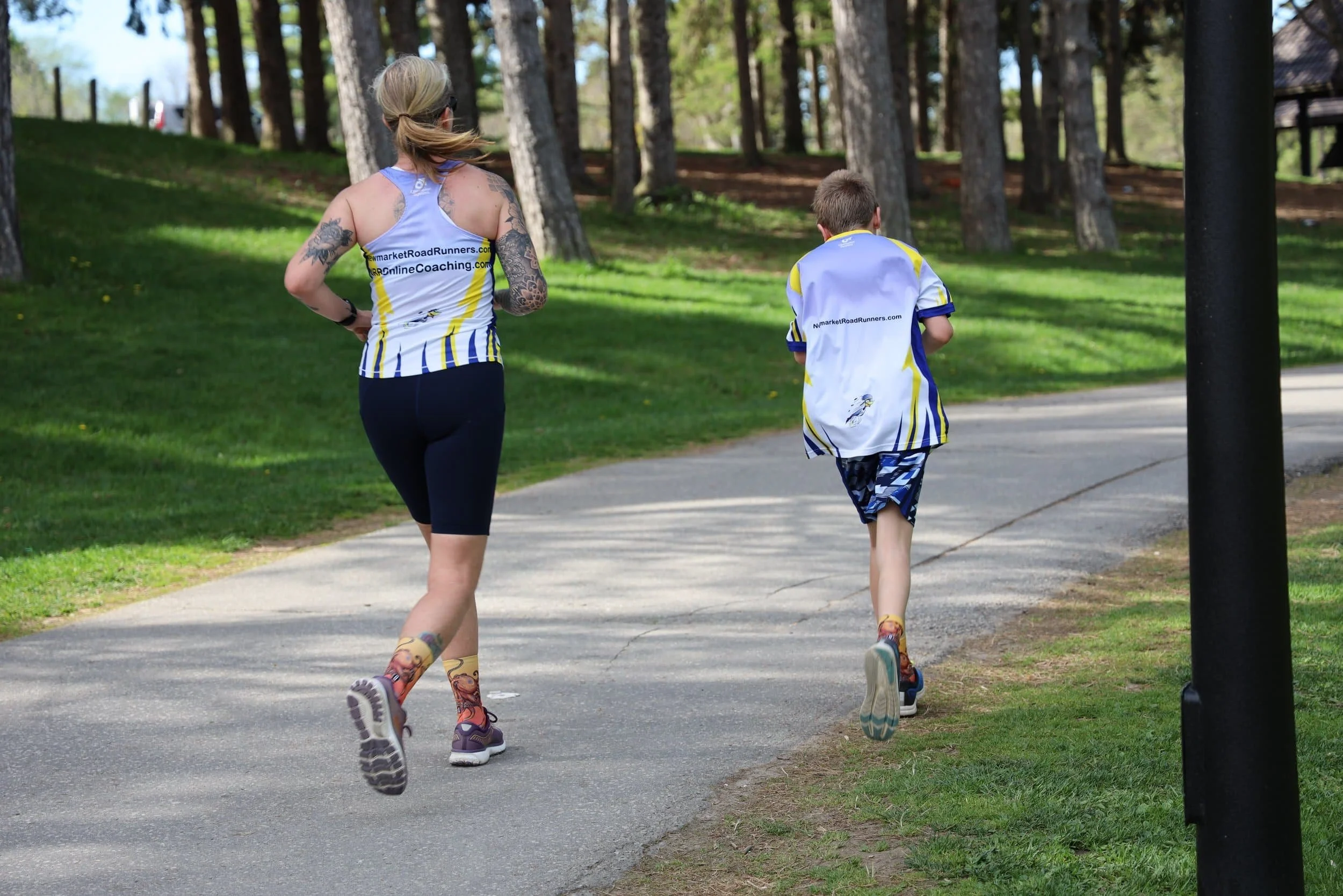 mother running with her son on a path through an area with tall trees