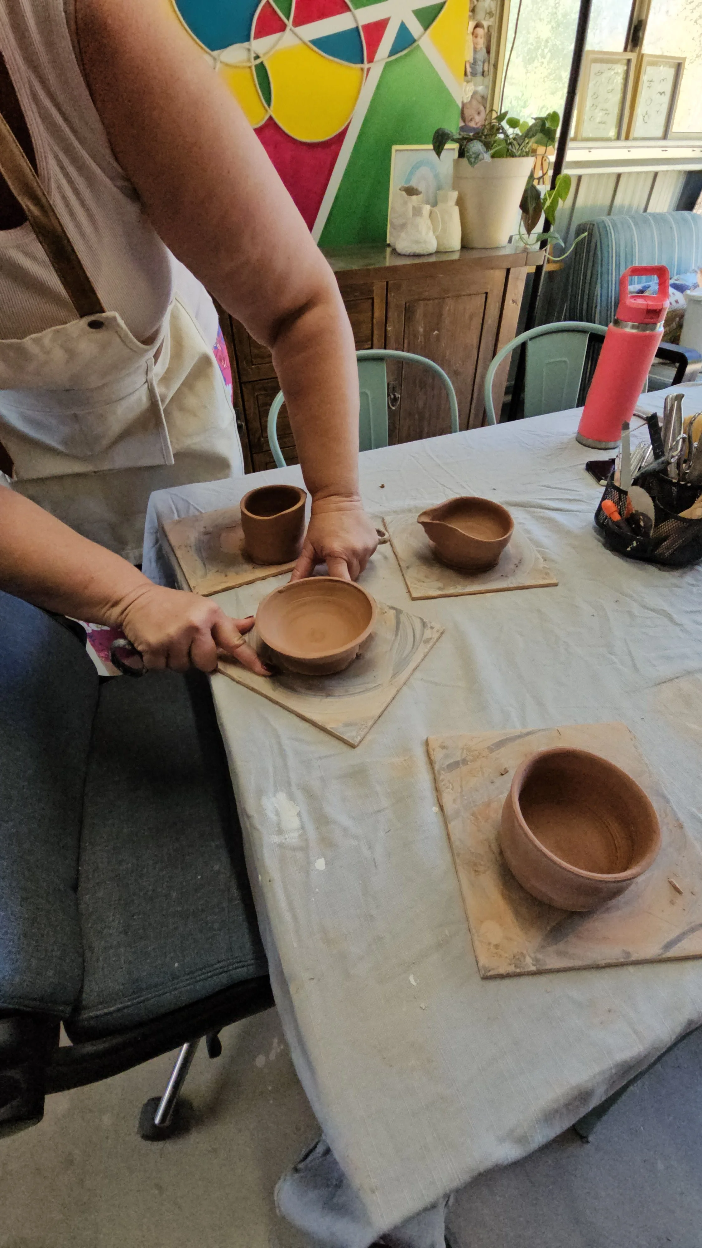 A potter carefully wiring a finished piece off the bat
