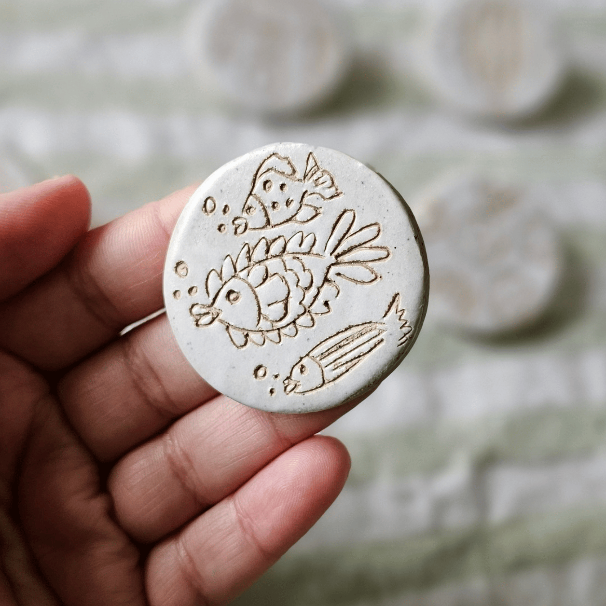 Brooch_sgraffito_white glaze_in hand_fish.png