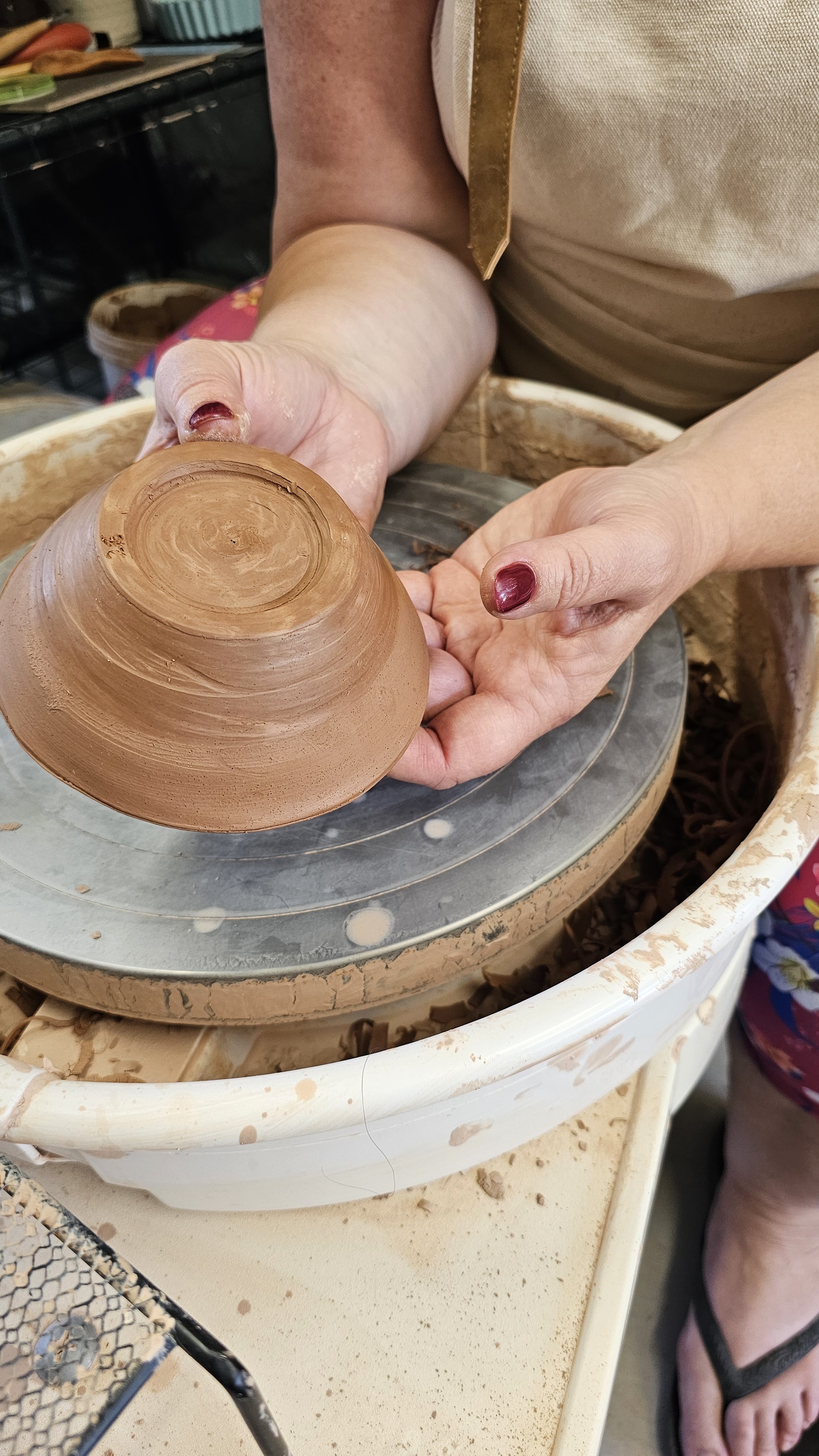 A potter shaping the base of a vessel during the trimming stage