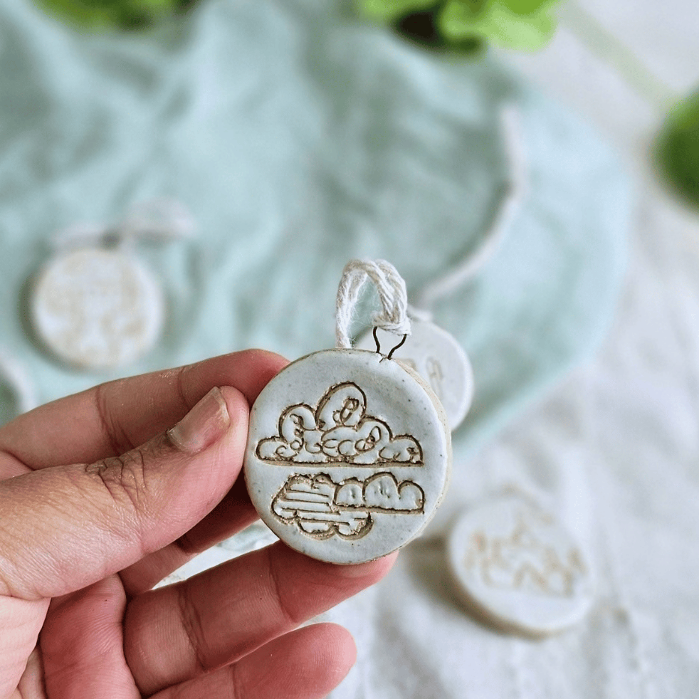 Mini Ornaments_sgraffito_white glaze_in hand_clouds.png