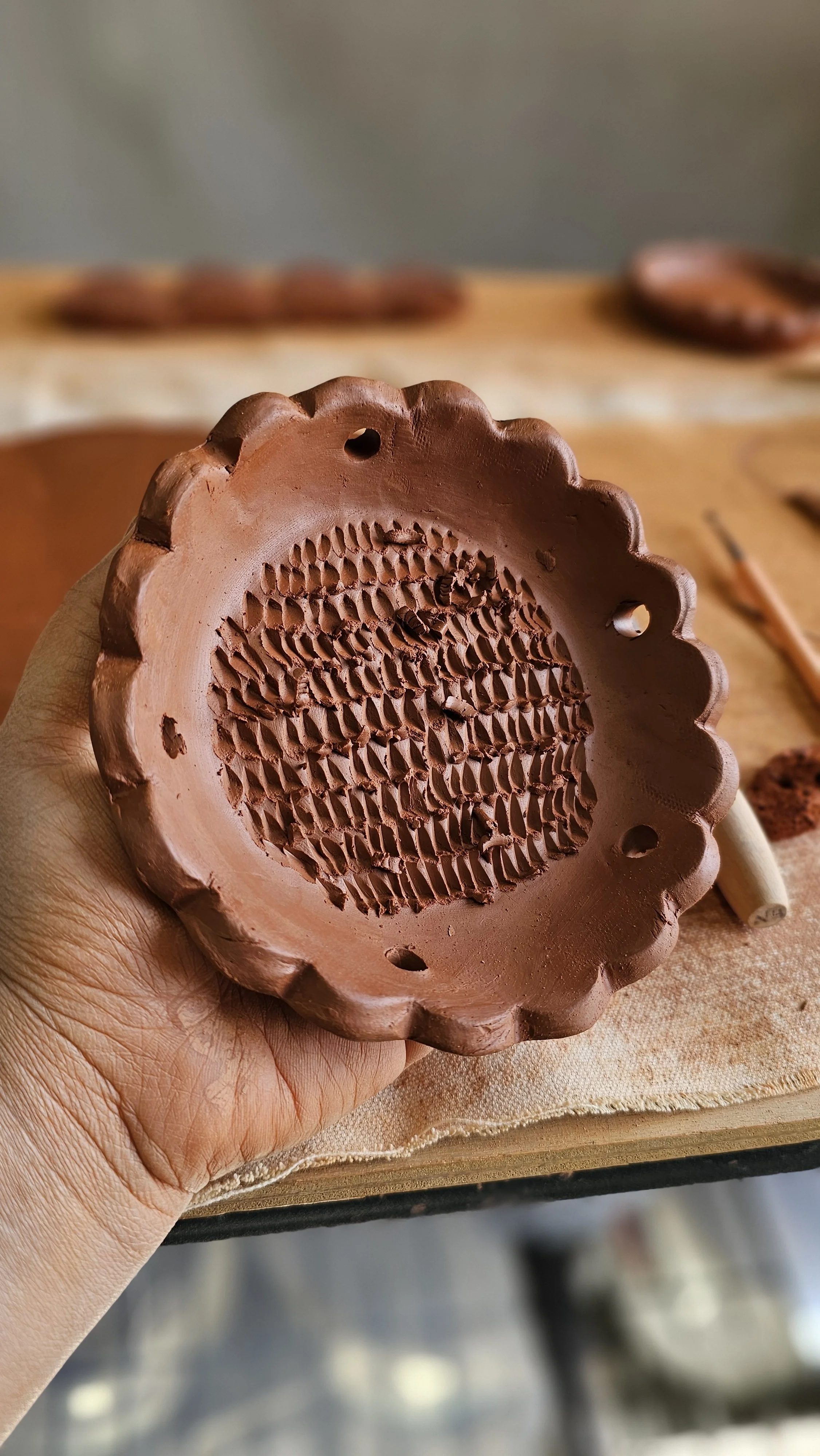 Ancient clay pottery including a vessel with a handle and a rounded object, displayed on a white surface with museum tools nearby.