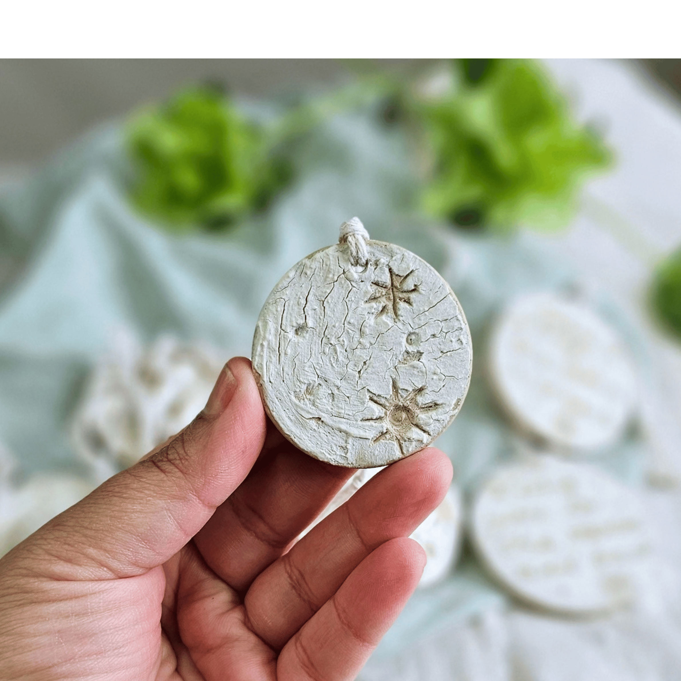 Moon Ornaments_sgraffito_white glaze_in hand_mmon with craters.png