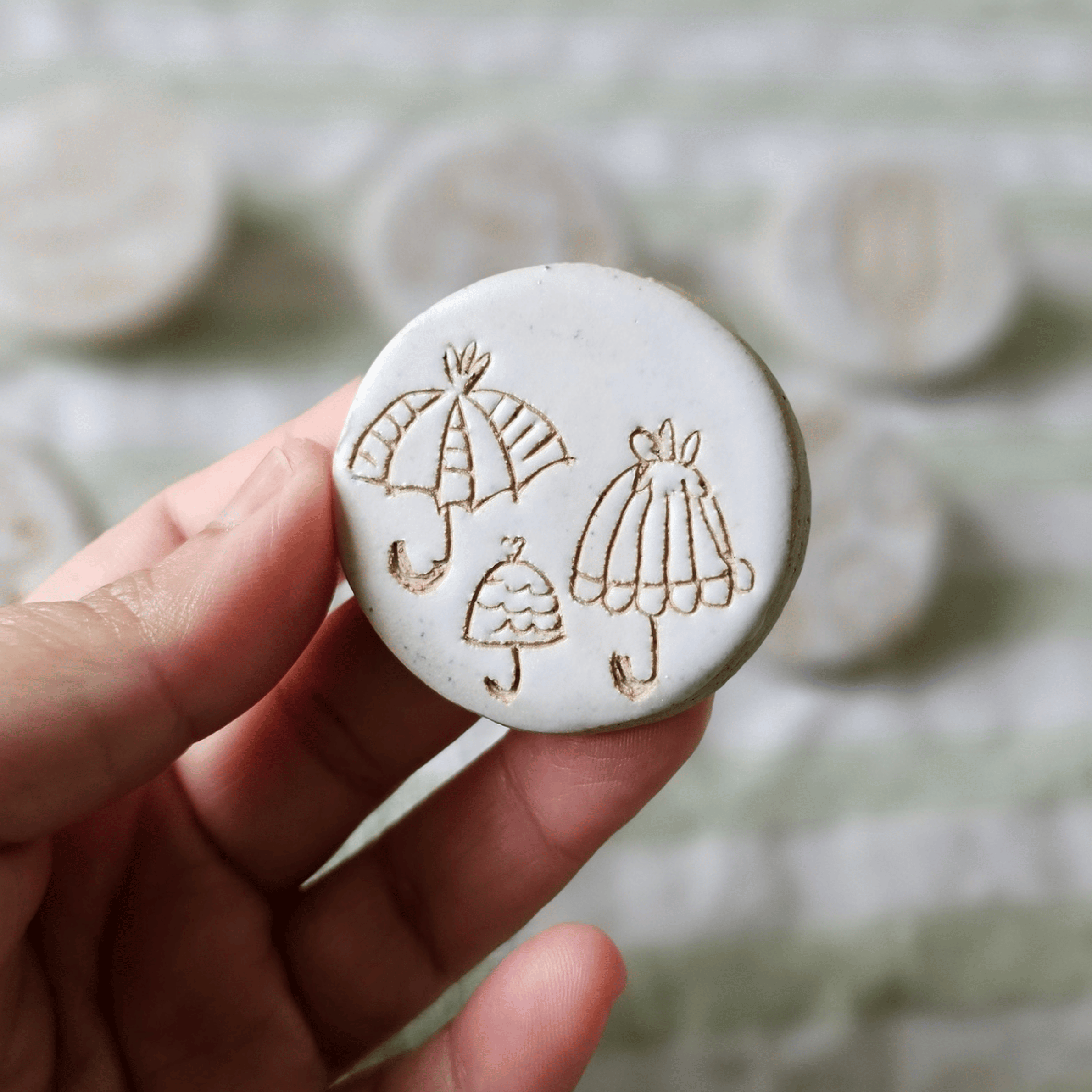Brooch_sgraffito_white glaze_in hand_umbrellas.png