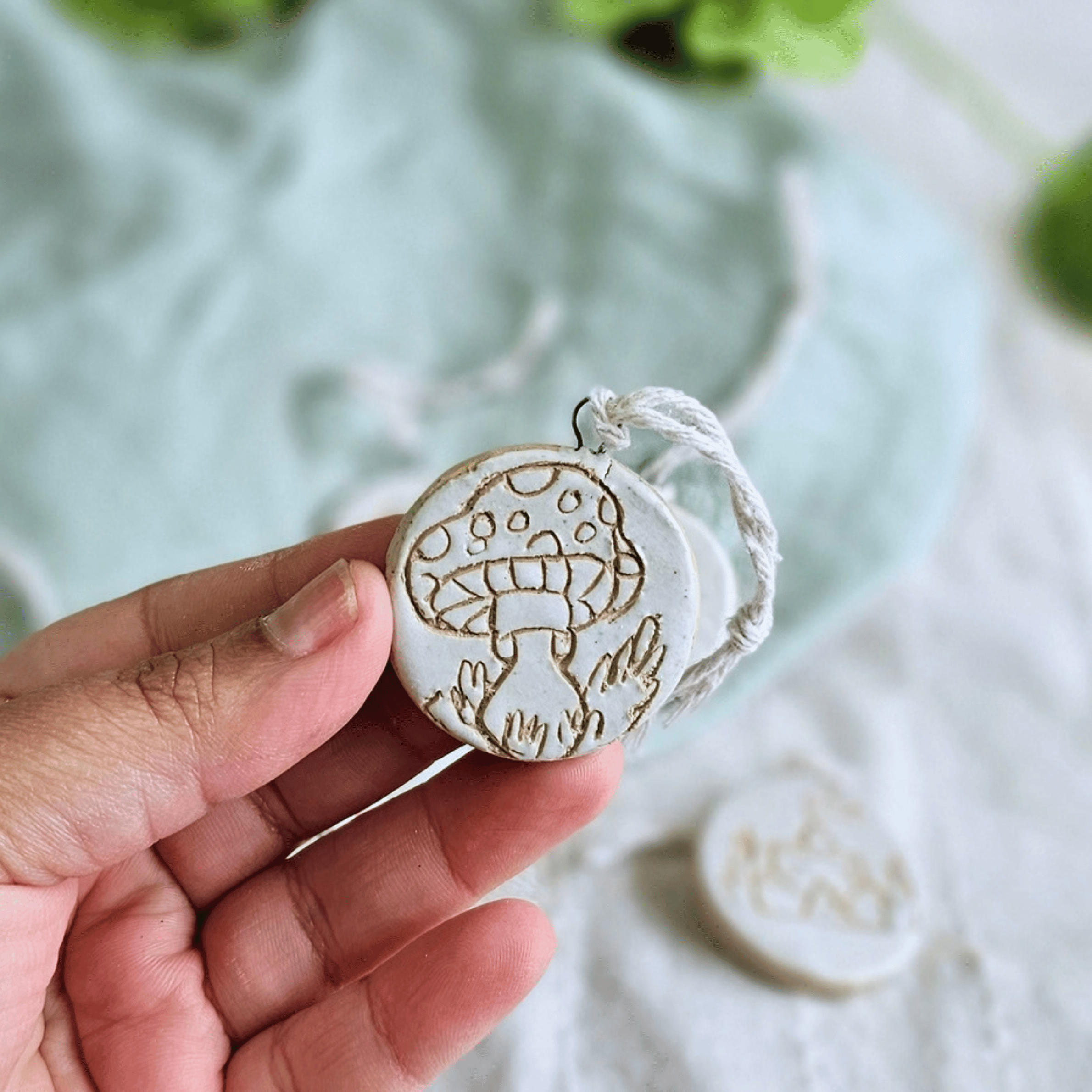 Mini Ornaments_sgraffito_white glaze_in hand_mushroom.png