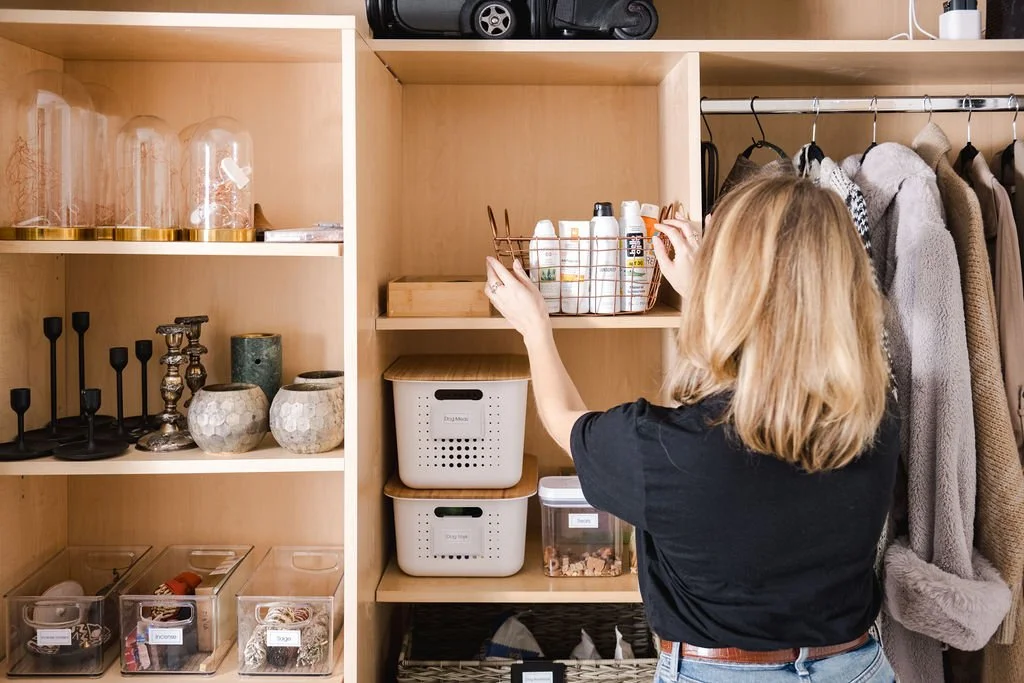 professional organizers arranges bins inside organized entryway closet