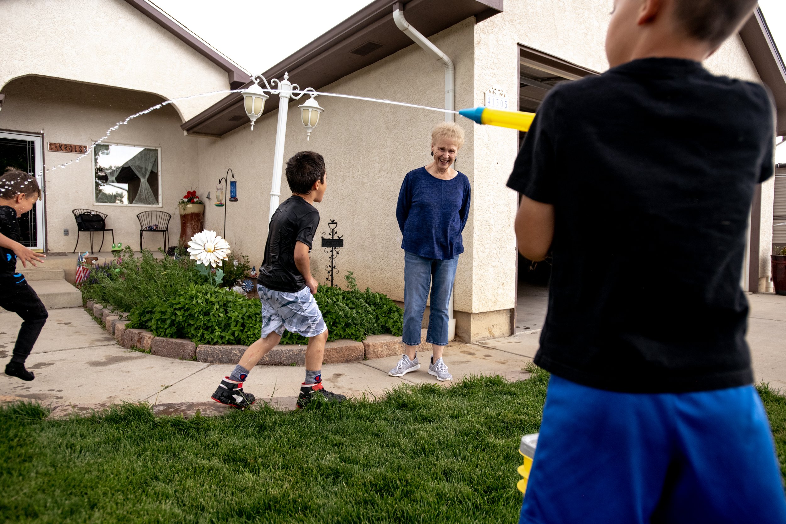  Cora Krol watches as three of her foster kids have a water fight in their front yard on Tuesday, May 30, 2023, near Pueblo, Colo. Cora and her husband Stan — who are in their 70s — have been fostering children for 34 years and have brought in more t