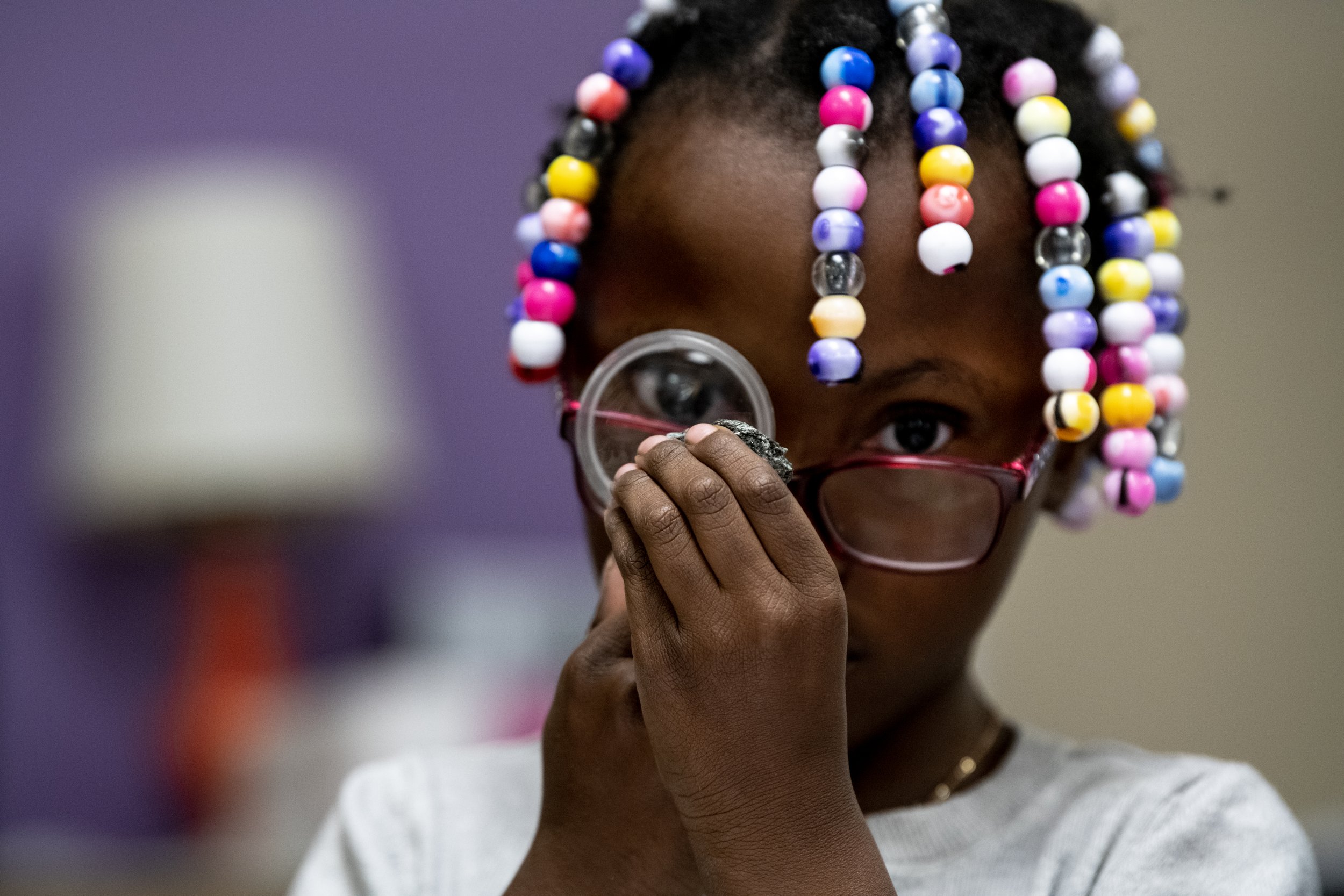  Kacia Williamson examines a rock through a magnifying glass during a second-grade science class on Wednesday, Oct. 26, 2022, at James Monroe Elementary School in Colorado Springs, Colo. 