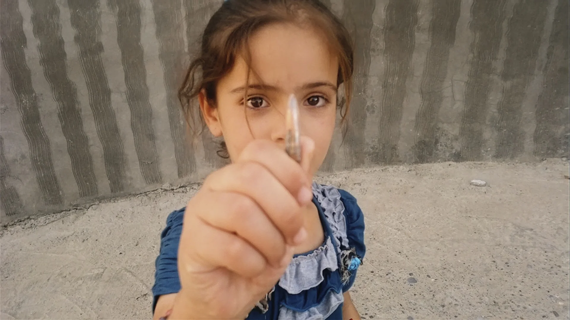 Sarah, datter til sykepleier Nori Sharif, viser fram en geværkule hun har funnet.