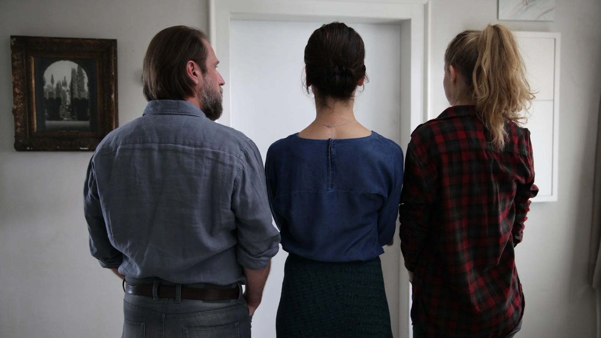 Far (Bjarne Mädel), mor (Bibiana Beglau) og datter (Emma Bading) står utenfor døra der familiens 17-åring har stengt seg inne for godt. Fra filmen 1000 Arten, den Regen zu beschreiben av Isabel Prahl.