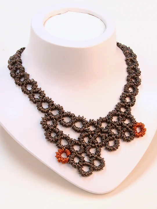  This piece is copper-, and black-colored copper chainmaille in an asymmetrical circular pattern. It's a one-of-a-kind piece with a spring clasp. 