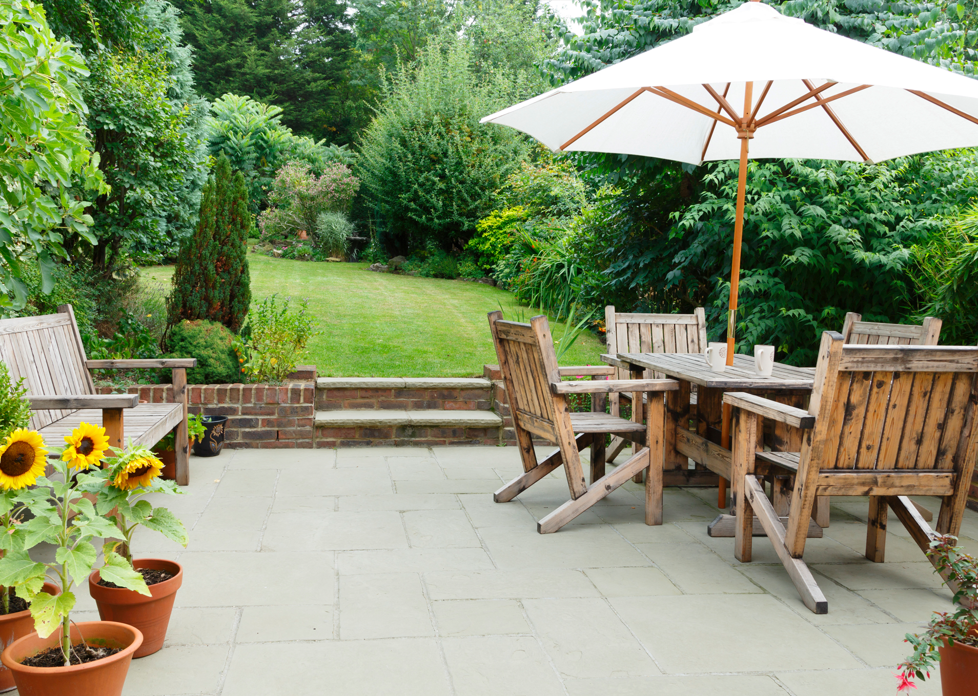 Backyard patio with sunbrella and lawn with beautiful landscape