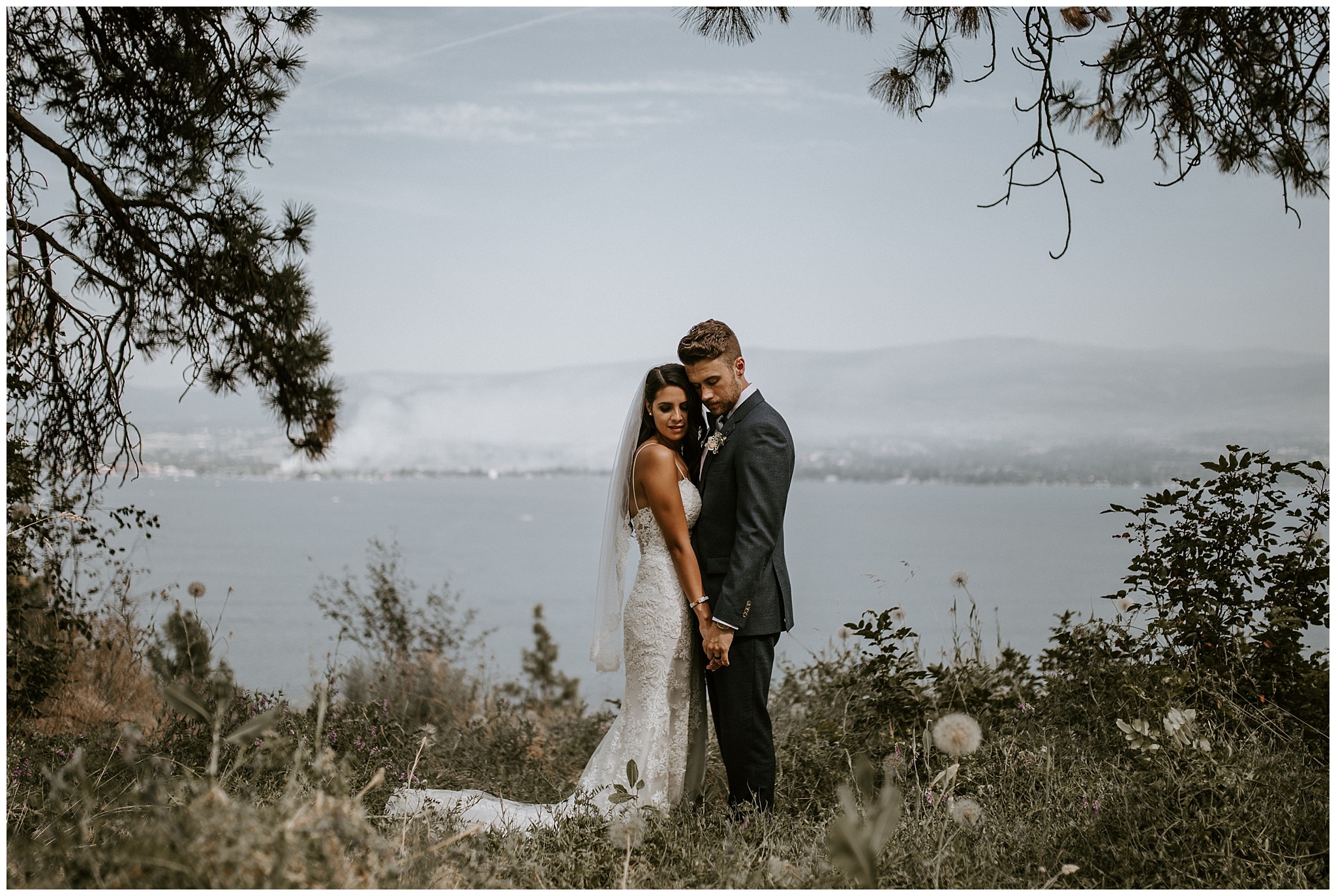 A bride and groom in front of a view of Okanagan Lake 