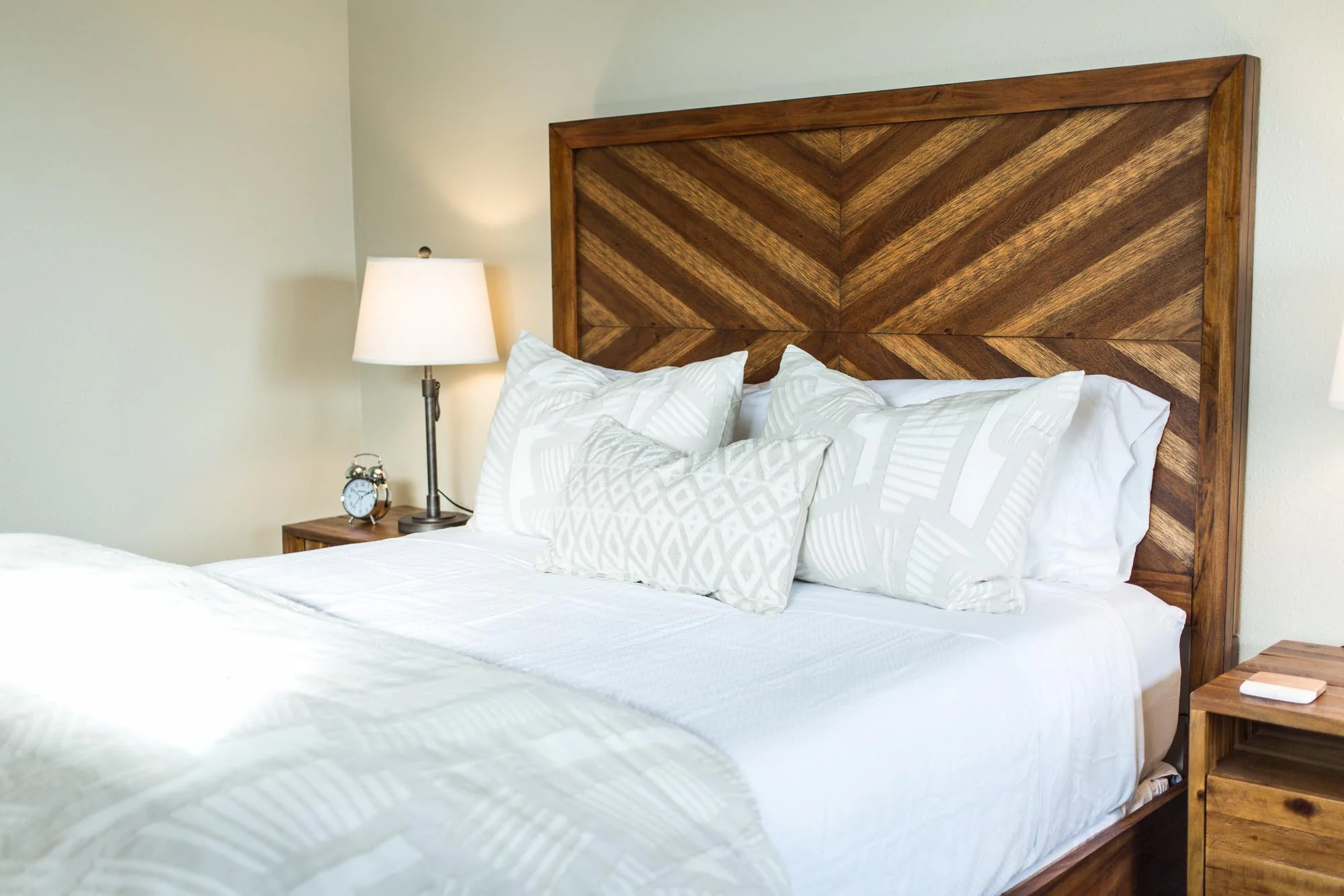 High backed wooden bed frame with bright white bedding
