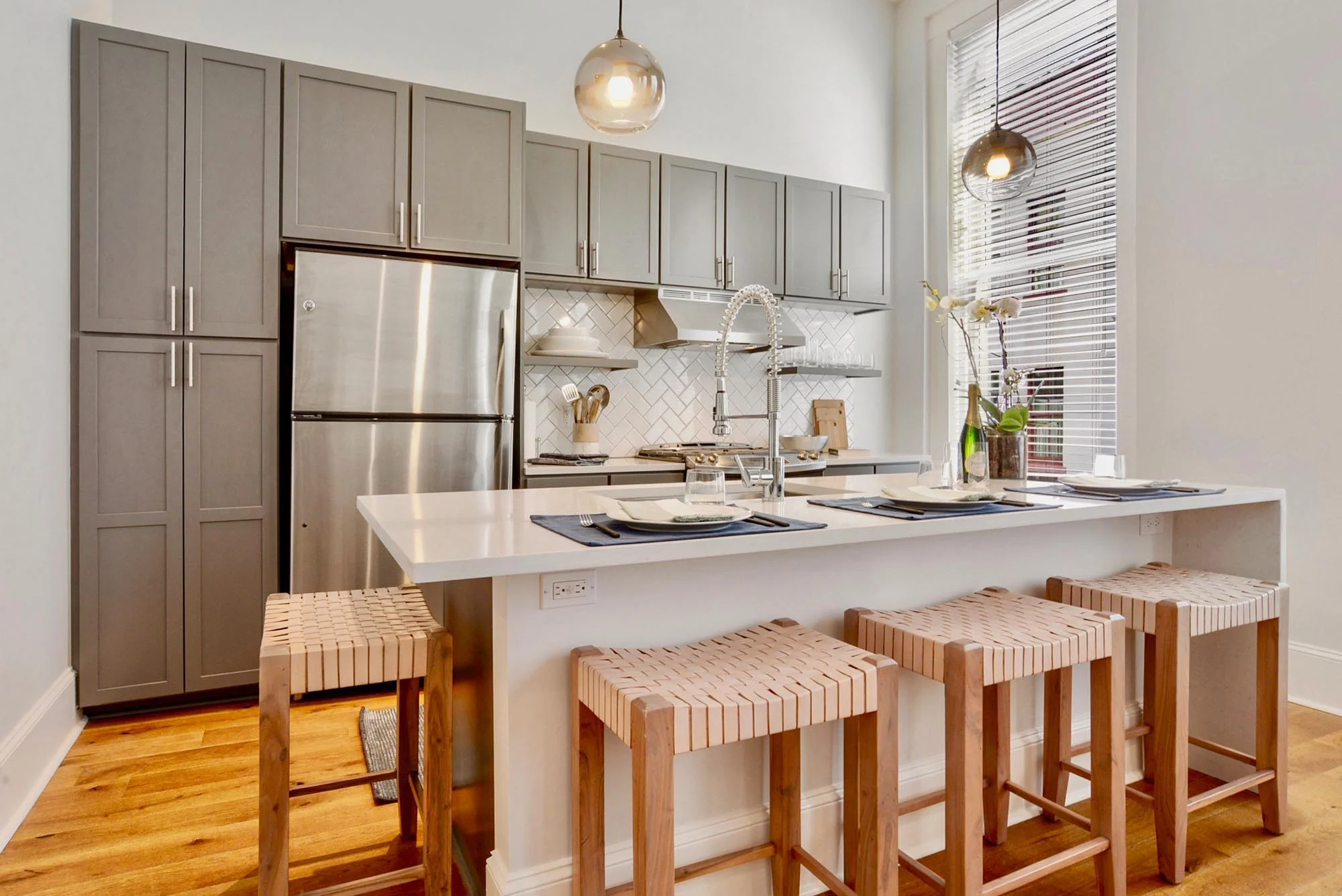Modern kitchen area with white quartz island and wooden stools