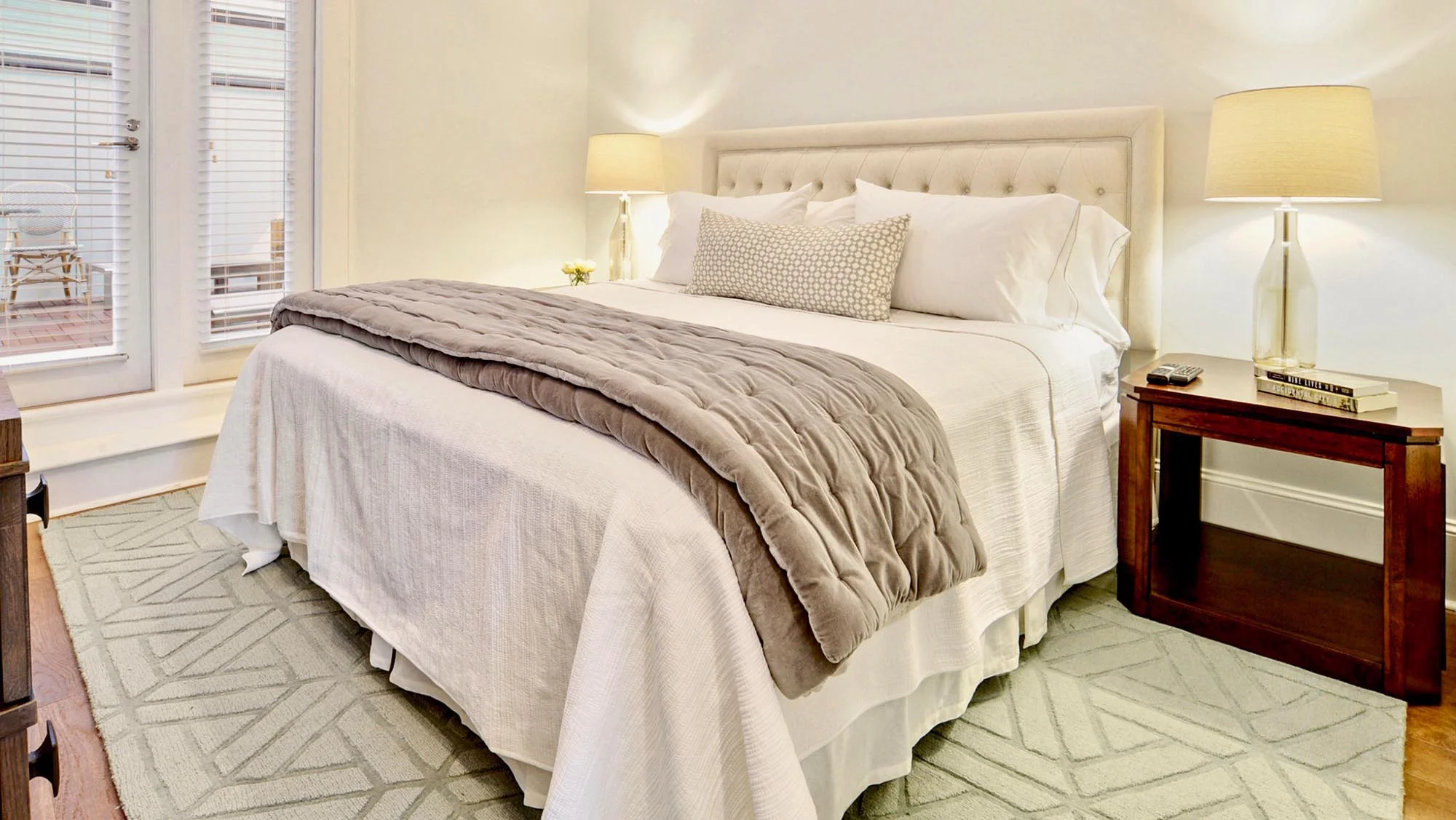 Bright white and navy bedroom with x bedside tables and lucite lamps