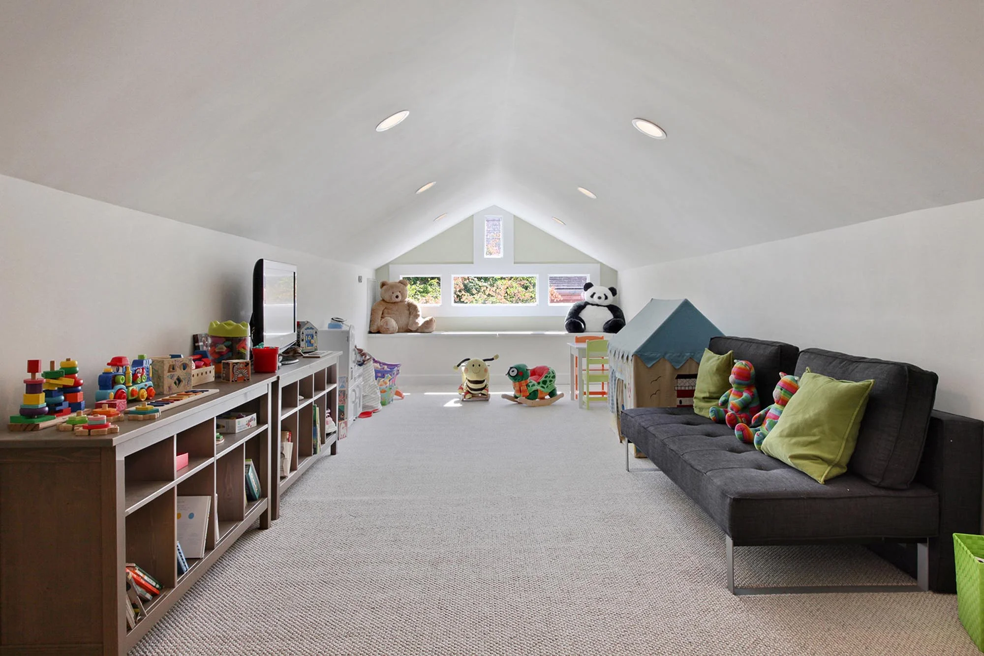Large attic loft with children’s toys on shelves and a guest futon bed