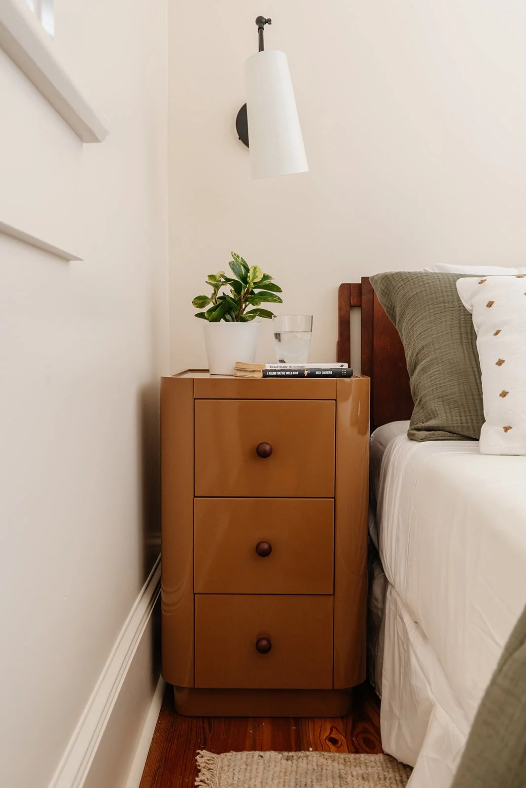 Bedroom vignettes: Primary bedroom with lacquer nightstand and wall sconce in a gut renovated New Orleans home