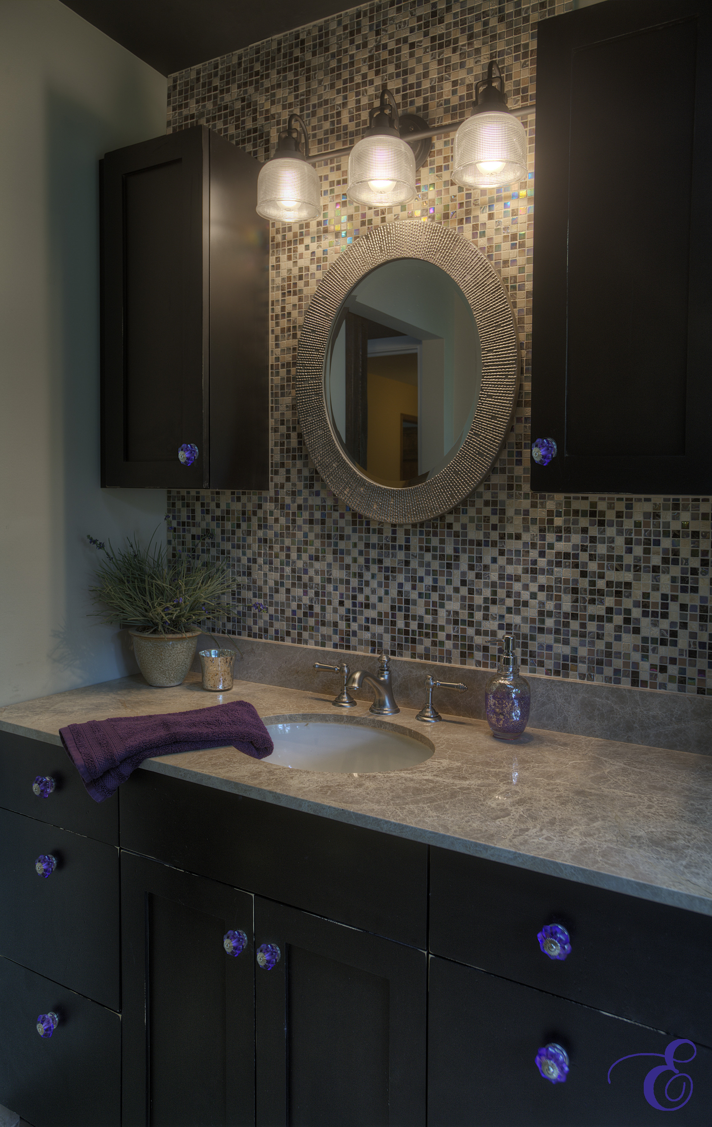 Distressed black cabinets with purple glass knobs against a tile wall