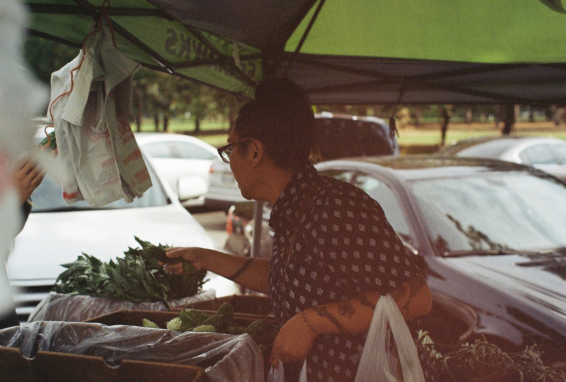 The author visiting Auntie L.'s tent, one of the Ilokano farmers at the Filipino Farmers Market in Seattle, WA. The farmers hail from generations of Filipino-Americans who settled in Wapato, WA who continue to farm there. / Photo by Thanh Hằng Phạm 