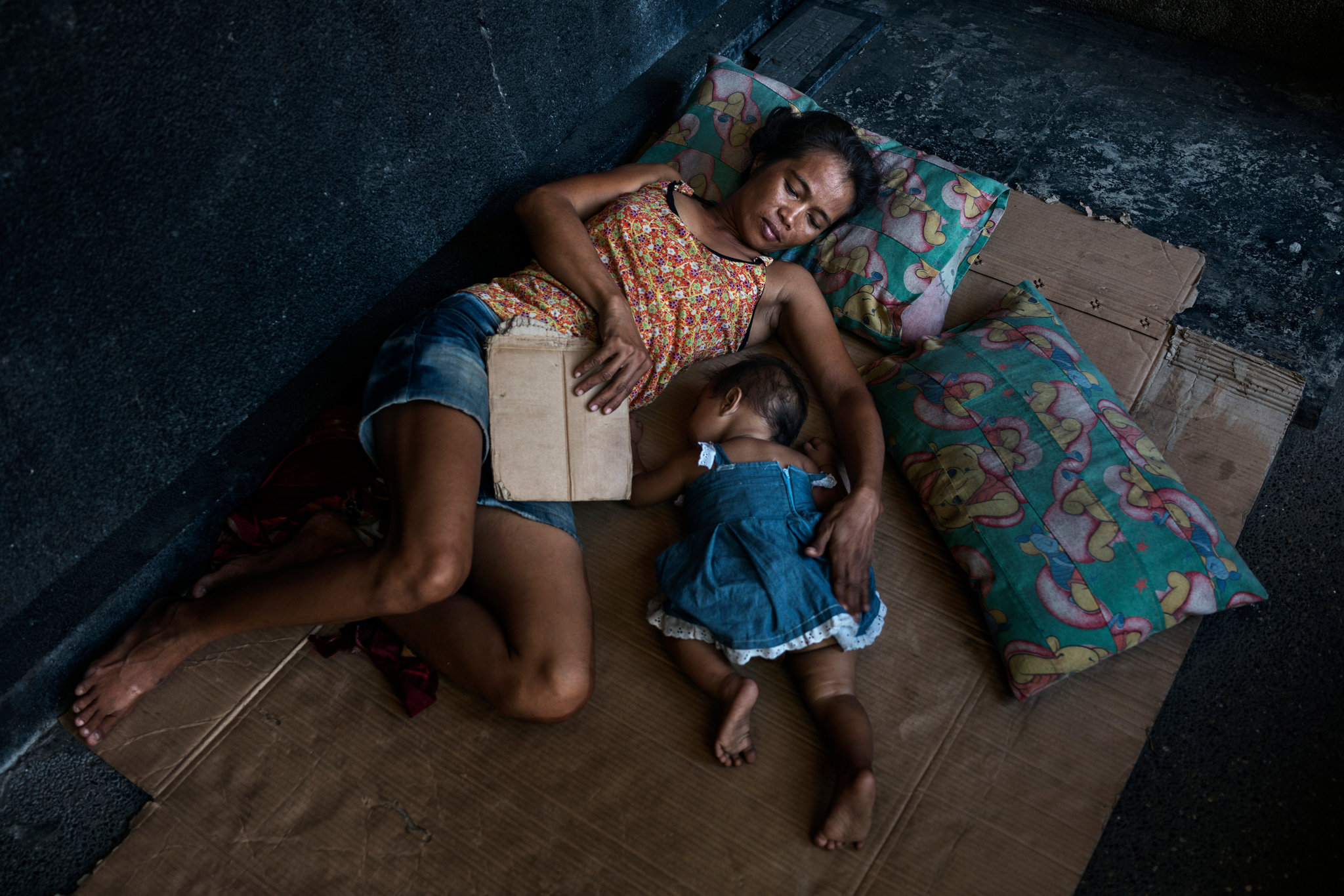 Noemi Canilang, 41, resting in a family mausoleum with her 8-month-old grandchild. She has cared for the mausoleum for 25 years and sleeps there with five members of her family. She receives a monthly stipend of 50 pesos, about $1. (Adam Dean for The New York Times)