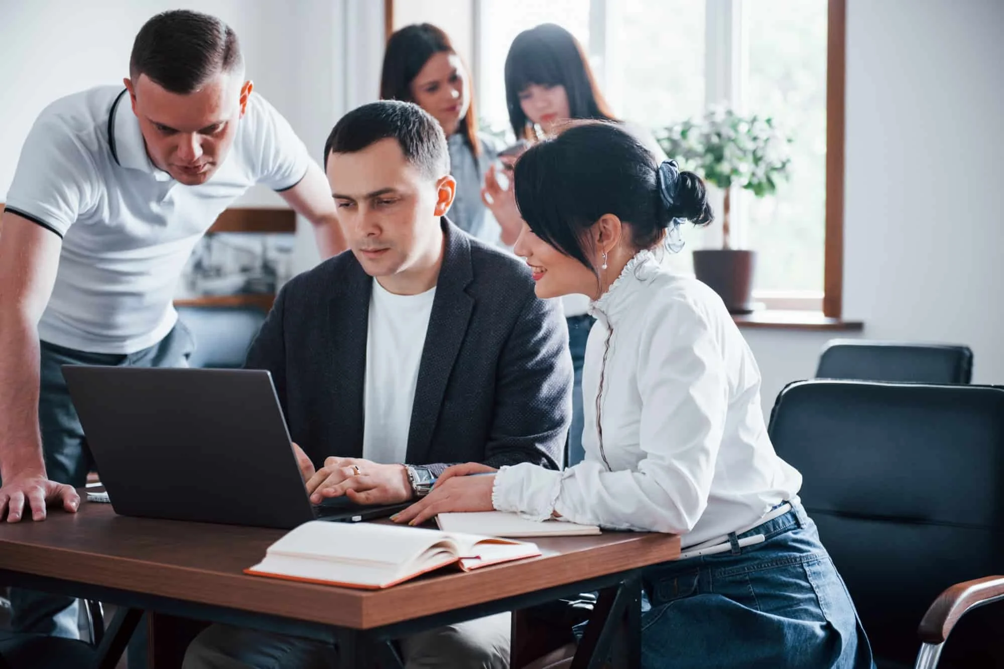 Image of multiple people watching as a man works on a laptops
