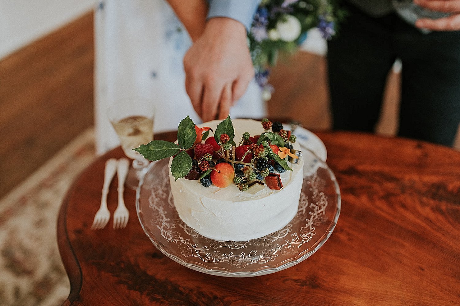 cutting small wedding cake with berries and flowers | full-service destination wedding | get married in Denmark | Aero Island | Danish Island Weddings | Denmark wedding planners and venue