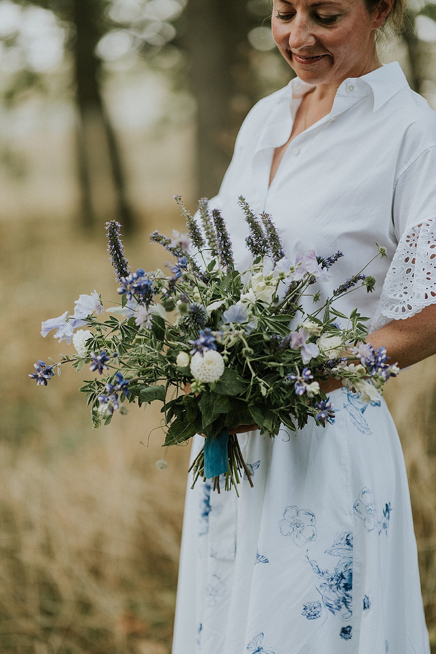 woman in white and blue dress holding fresh floral bouquet of green blue and white flowers  | Aero Island | Danish Island Weddings | Full service Denmark wedding planners