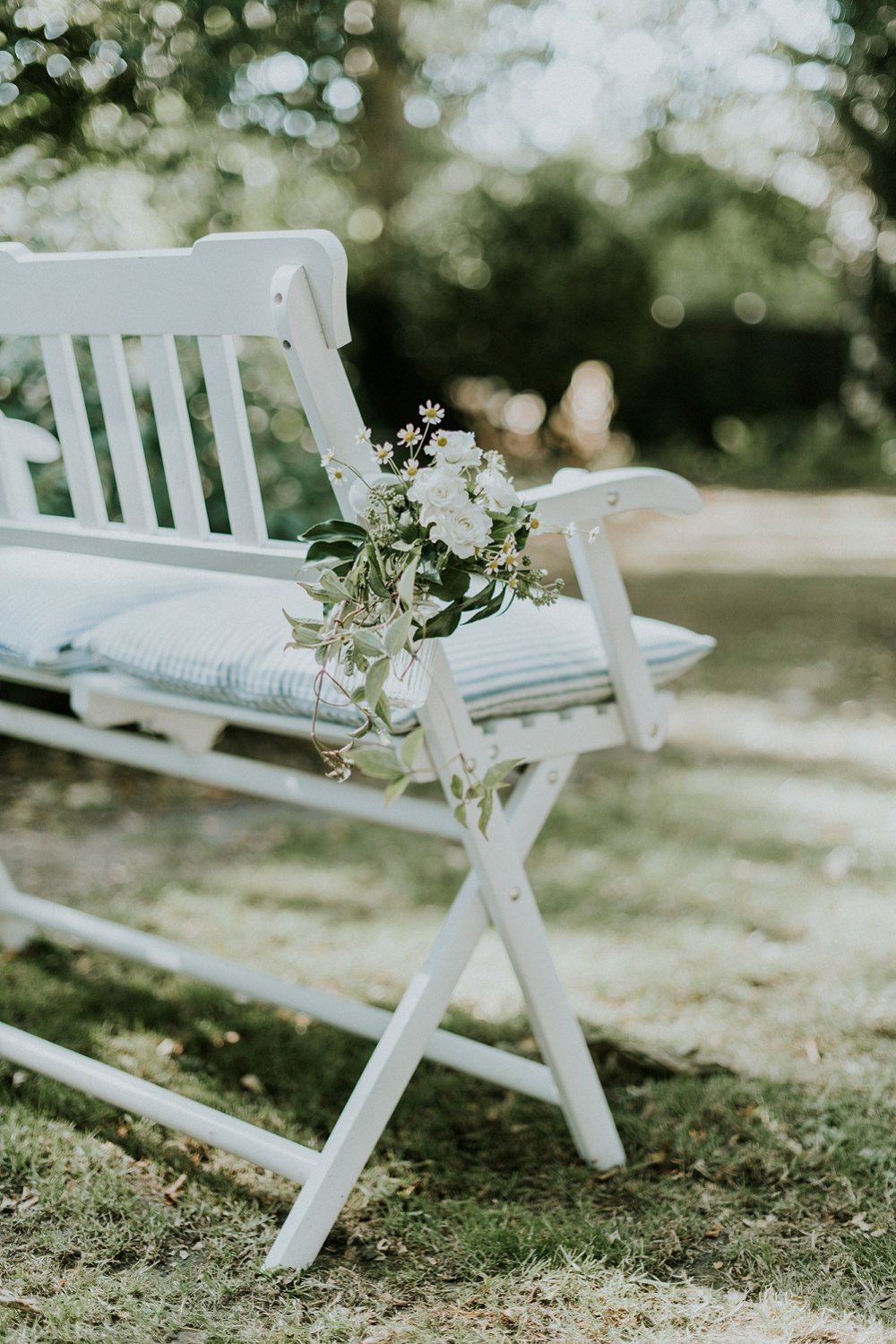 small floral arrangement tied to chair bench minimalist wedding decor aisle marker | Aero Island | Danish Island Weddings | Full service Denmark wedding planners