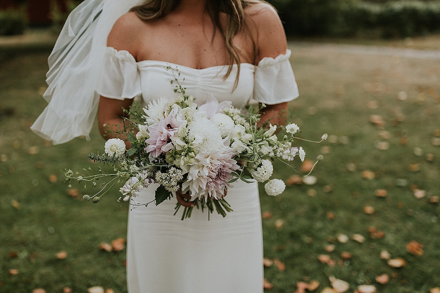 bride in off-the-shoulder dress carrying modern bouquet of fresh flowers | Aero Island | Danish Island Weddings | Full service Denmark wedding planners