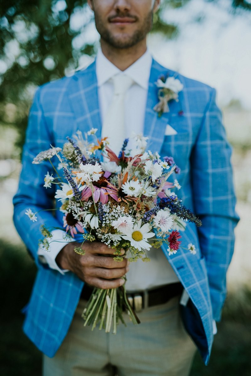 groom in blue checkered blazer holding fresh flower bouquet | Aero Island | Danish Island Weddings | Full service Denmark wedding planners