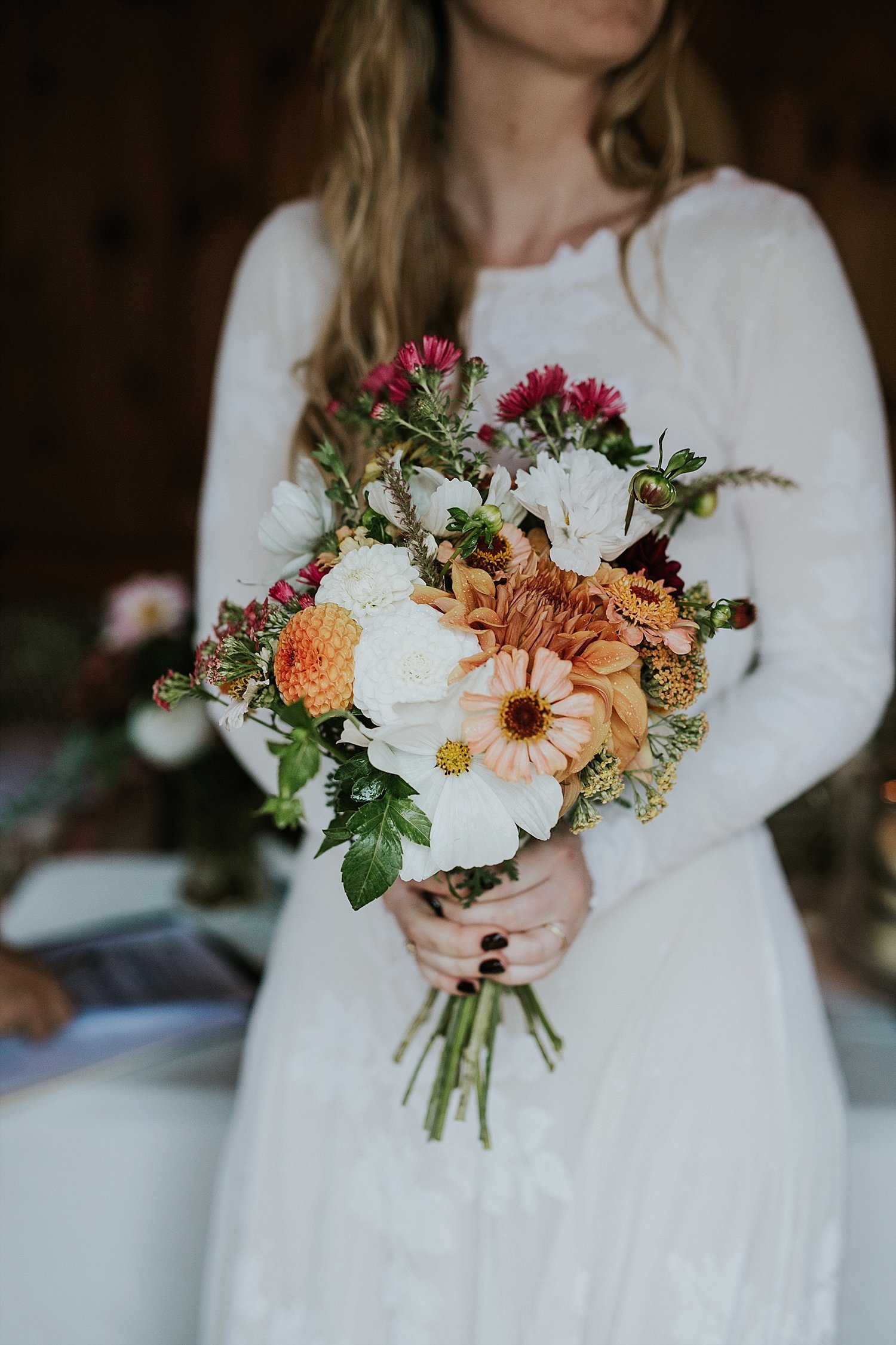 Bride holding bouquet of red, orange, peach, and white