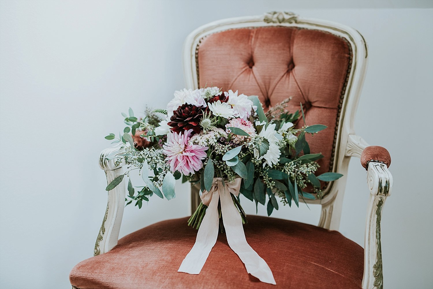 bouquet of flowers with ribbon on vintage chair | Danish Island Weddings | Full service Denmark wedding planners