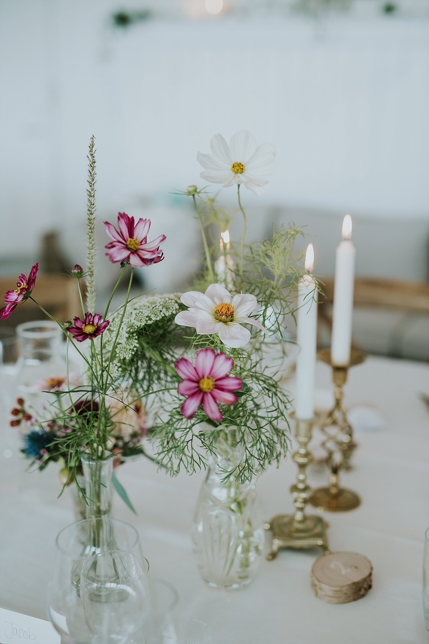 simple garden wedding floral arrangements in glass vases on table with candles | Aero Island | Danish Island Weddings | Full service Denmark wedding planners