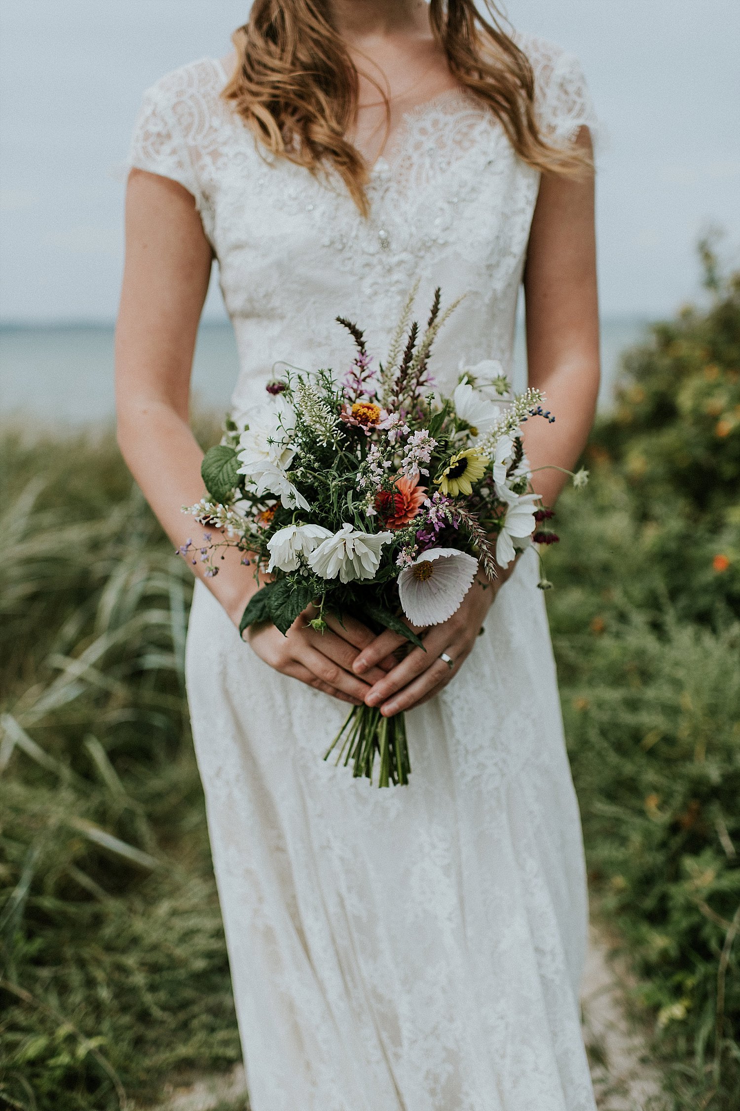 Bride holding floral bouquet on beach