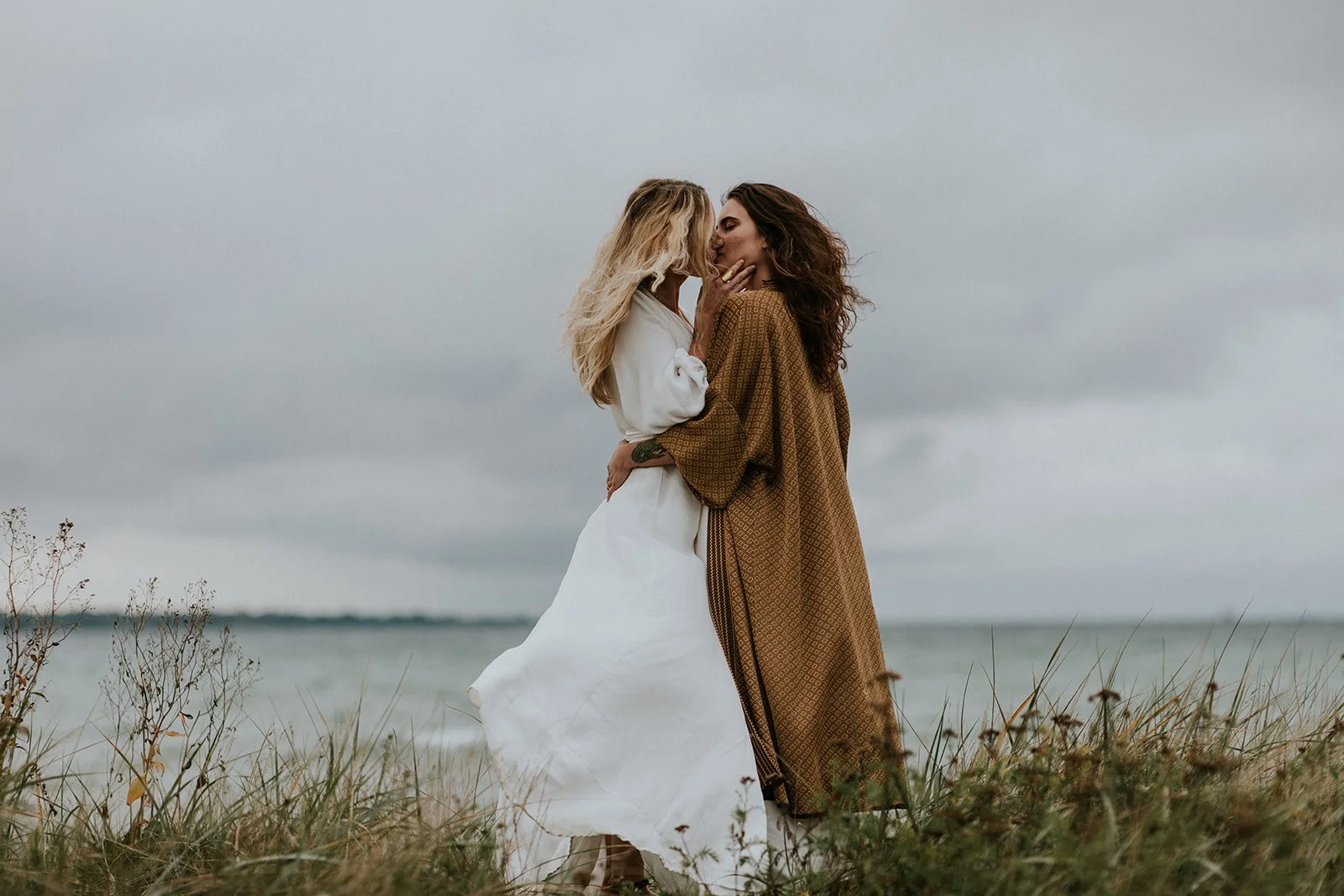Two brides sharing an intimate hug and a kiss during their beautiful same-sex micro wedding on a Danish island.