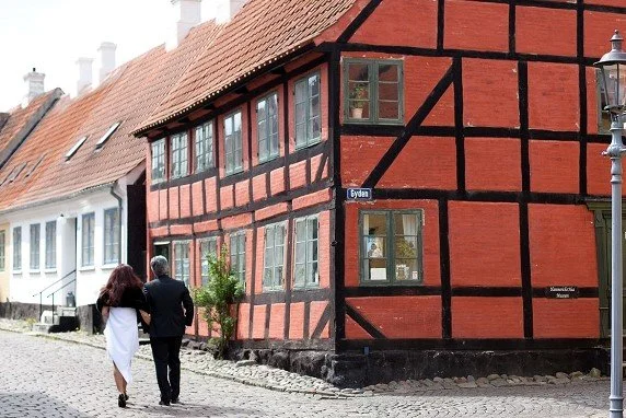 A wedding couple walking past the historic red half-timbered museum building in Gyden street in the old town of Aeroskobing.