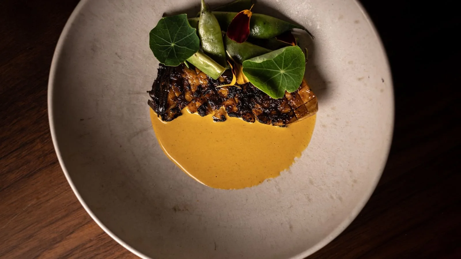 A beautifully plated gourmet dish featuring local ingredients and fresh greens in a ceramic bowl. Showcasing the high-end fine dining experience for couples on an elopement honeymoon on Aeroe Island in Denmark.