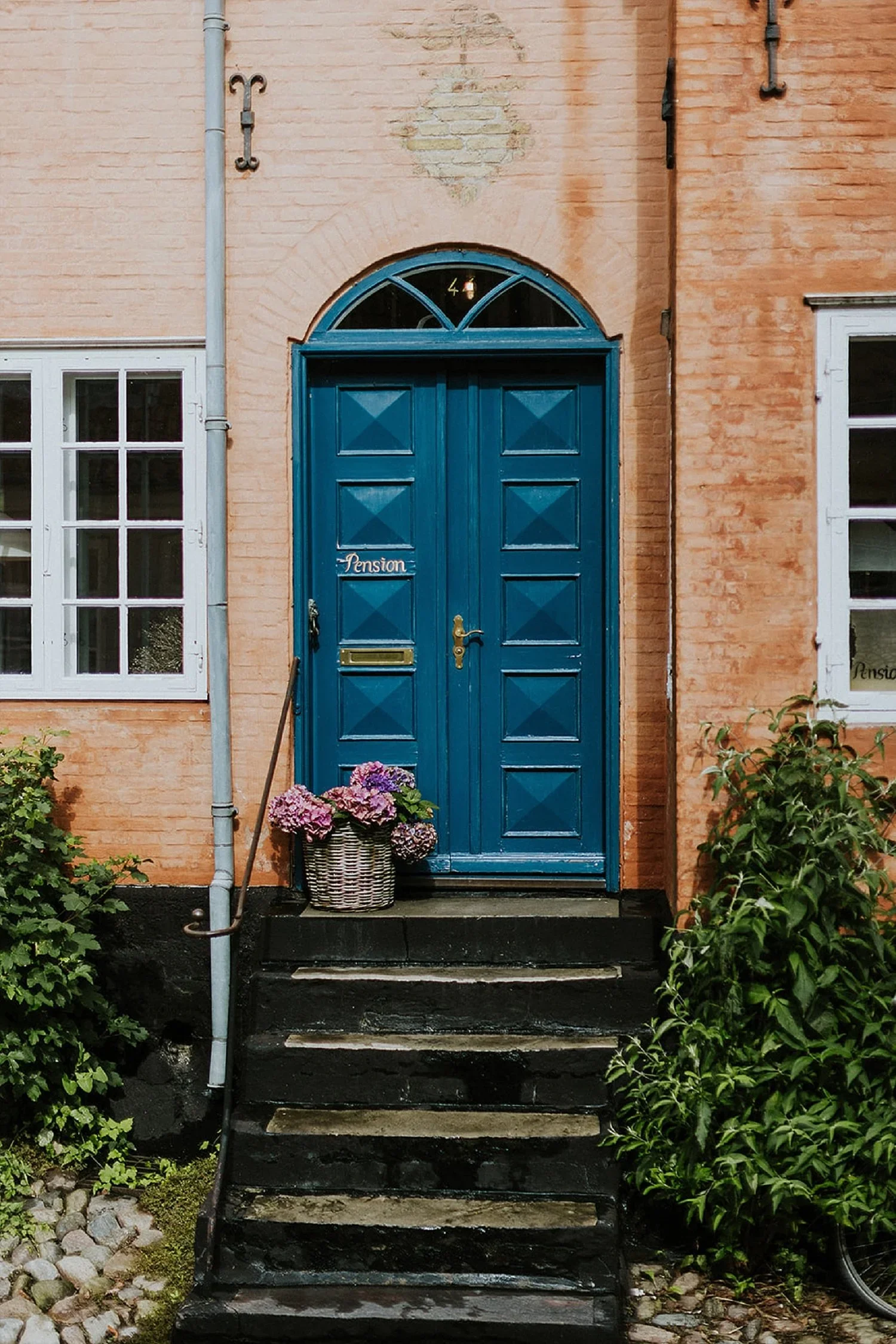 A close-up of the historic double blue wooden door at Vestergade 44 in Aeroeskoebing. An iconic architectural detail for couples planning a destination wedding or romantic elopement honeymoon on Aeroe Island in Denmark.