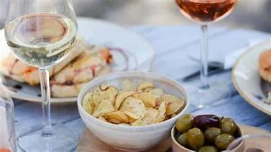 A close-up of a tapas picnic platter featuring fresh bread, olives, and spreads with a glass of white wine. Perfect inspiration for pre-concert dining at Soebygaard on Aeroe Island in Denmark.