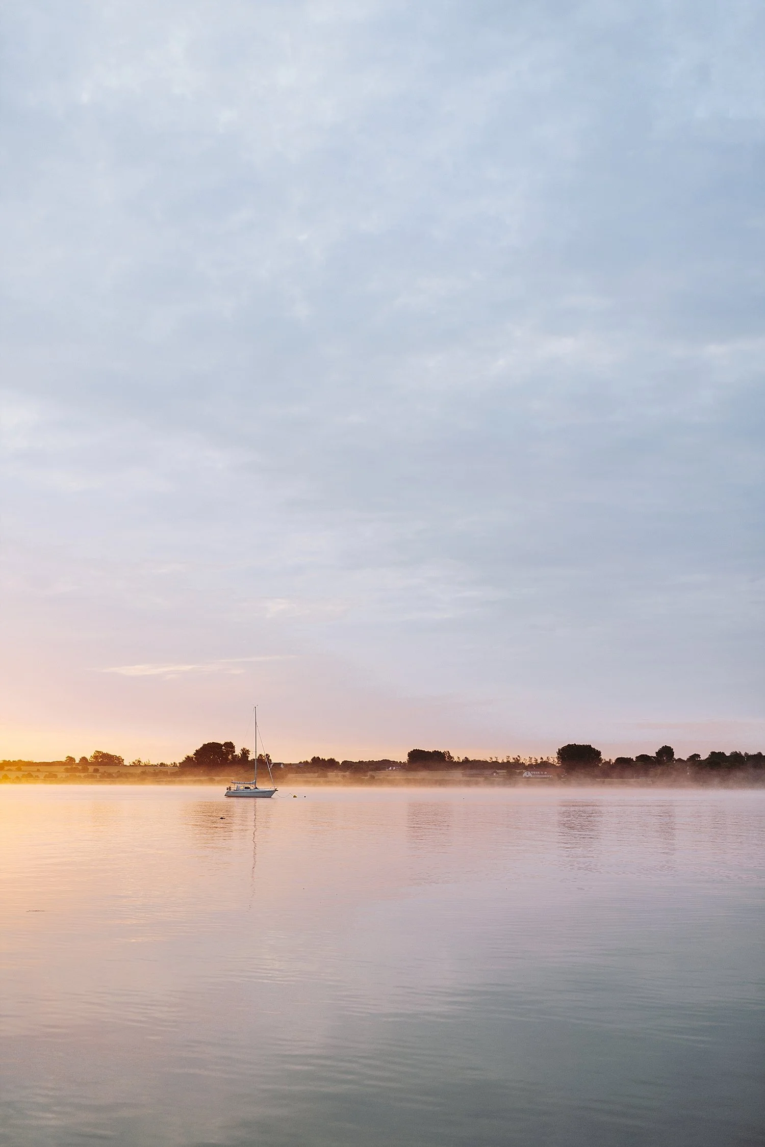 A peaceful sunset view over the calm sea with a sailing boat near Aeroe Island.