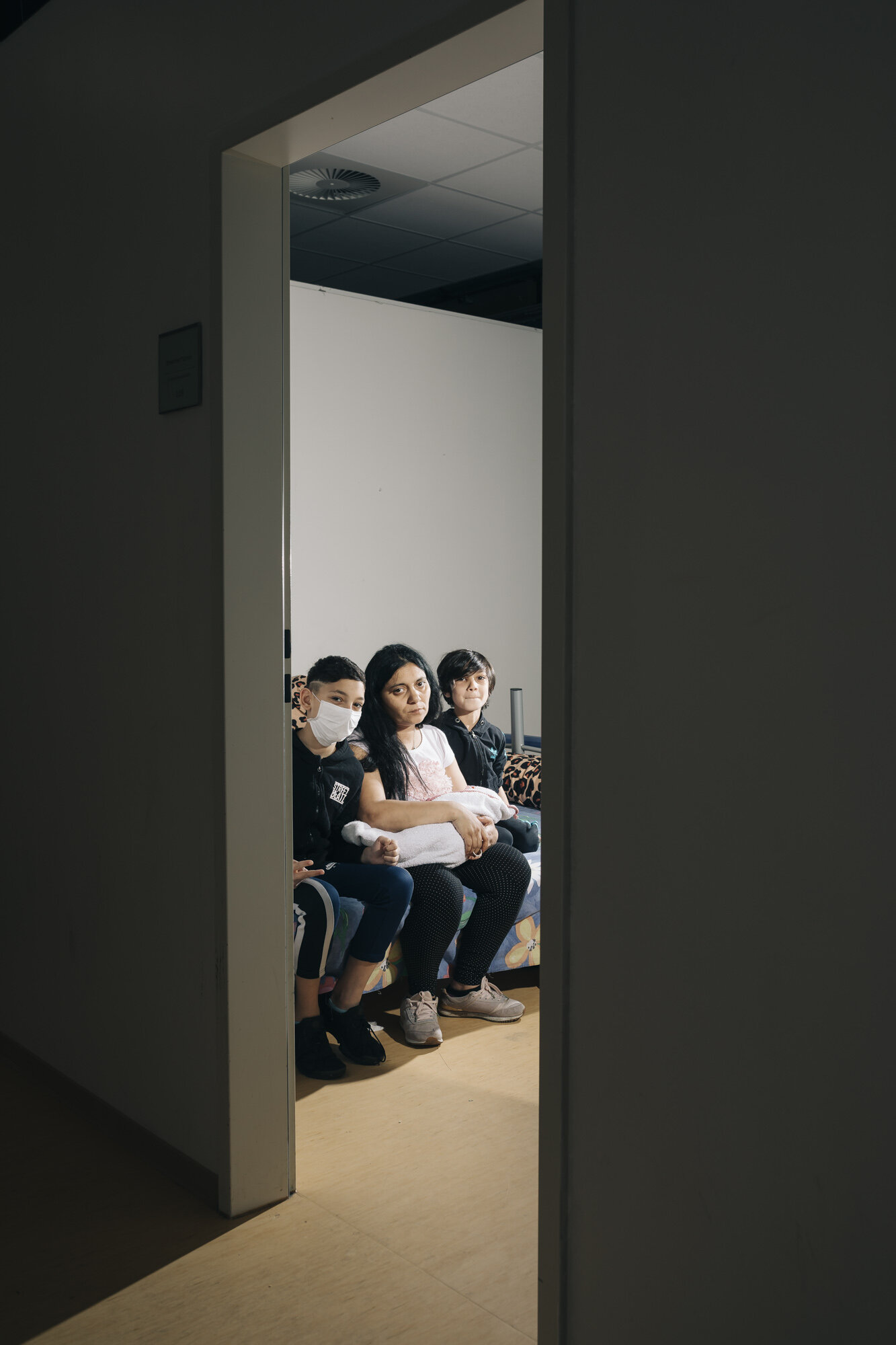  The Koćić family poses for a portait in their room in a refugee shelter. They live with five people in a room whose walls do not reach the ceiling in the refugee accomondation Lindenstrasse“. In April, 150 of 600 residents were infected here at the 