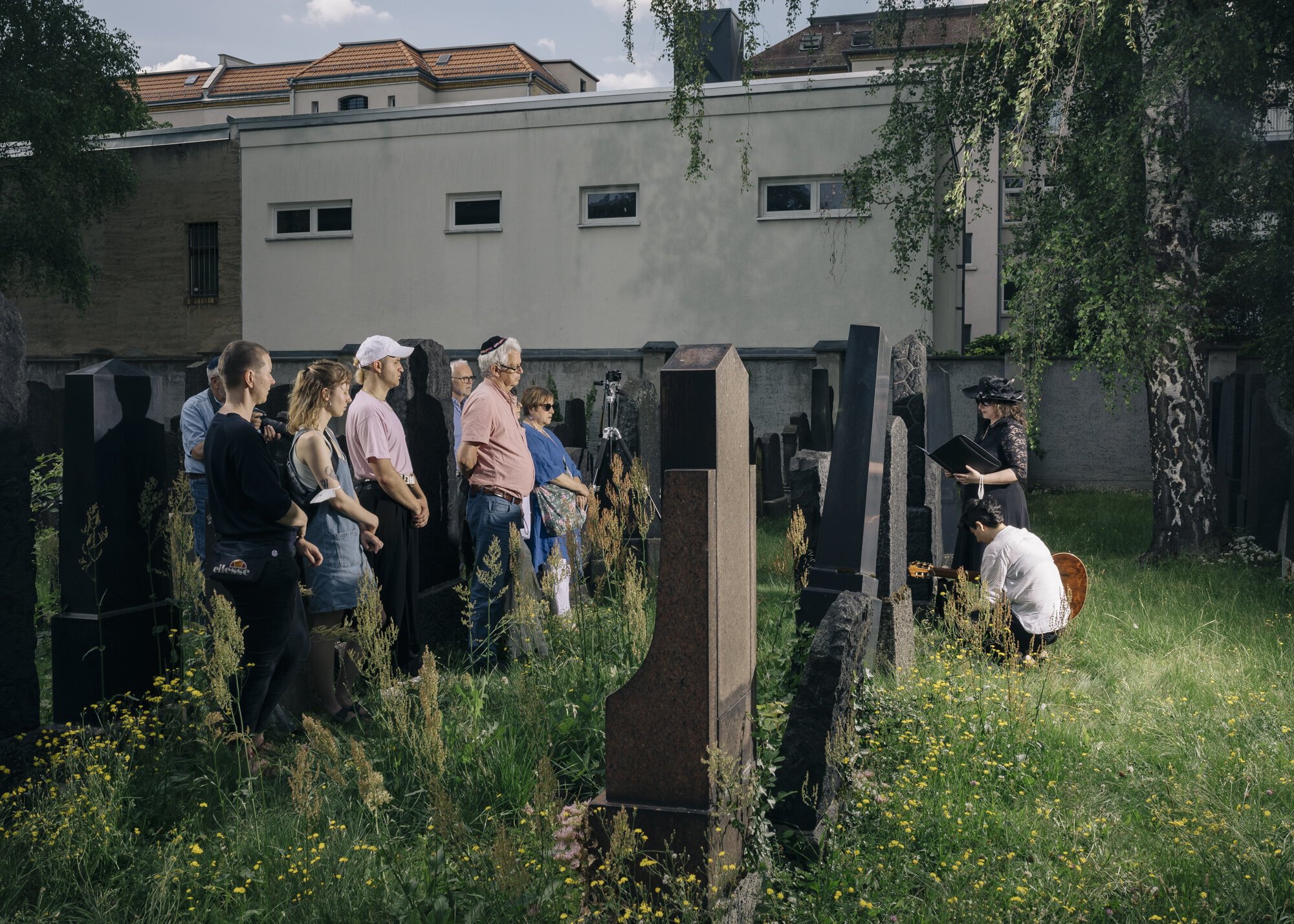  Peter M. (pink shirt) has travelled from Copenhagen for the "Jewish Week" to visit the grave of his ancestor "Esther Adelski" at the Jewish cemetery in Leipzig. At the grave, Rabbi Esther Jonas-Märtin holds a ceremony. Peter's family lives in Denmar