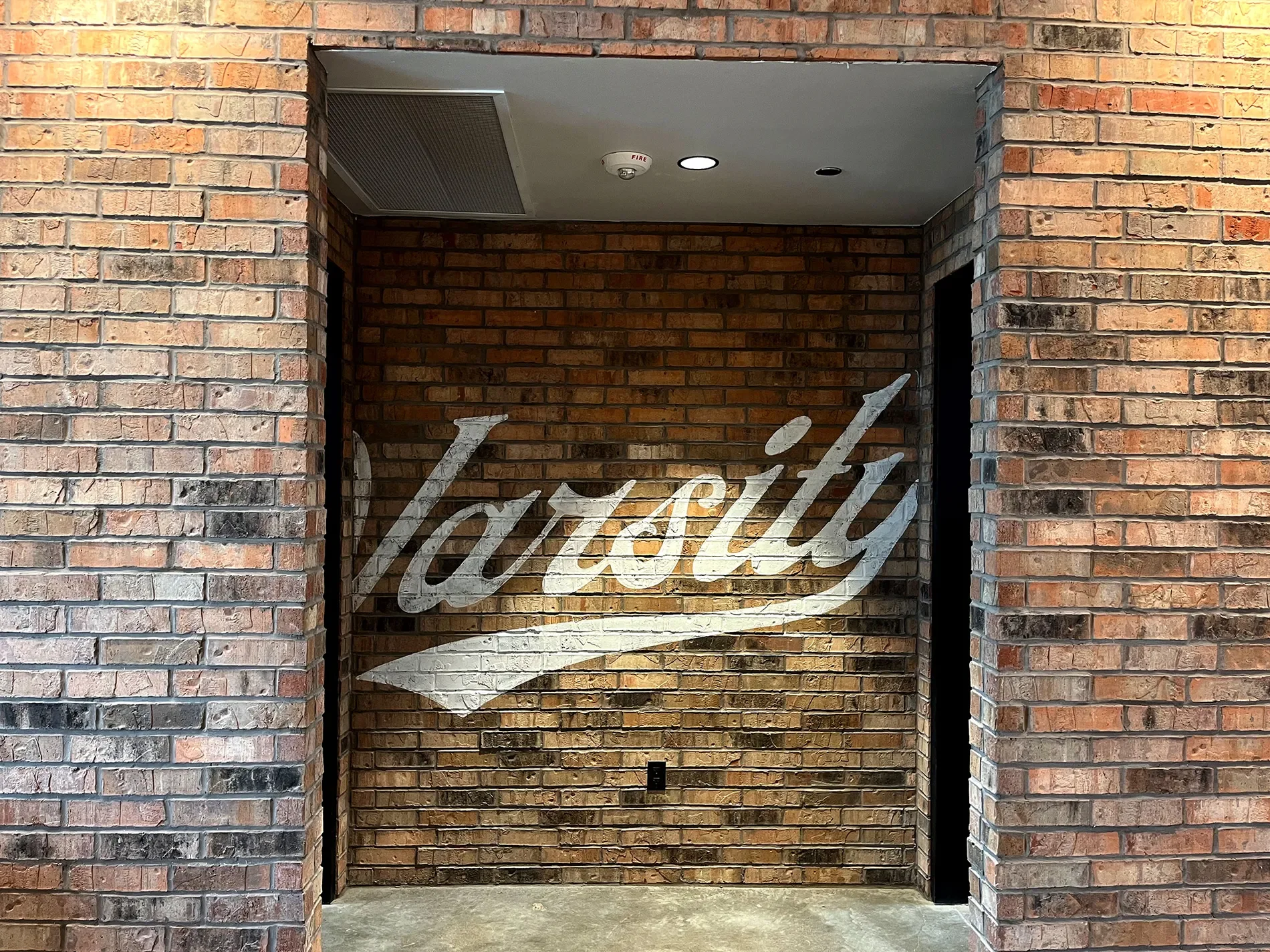 Brick wall with the word 'Luxury' painted on it in large, cursive white letters.