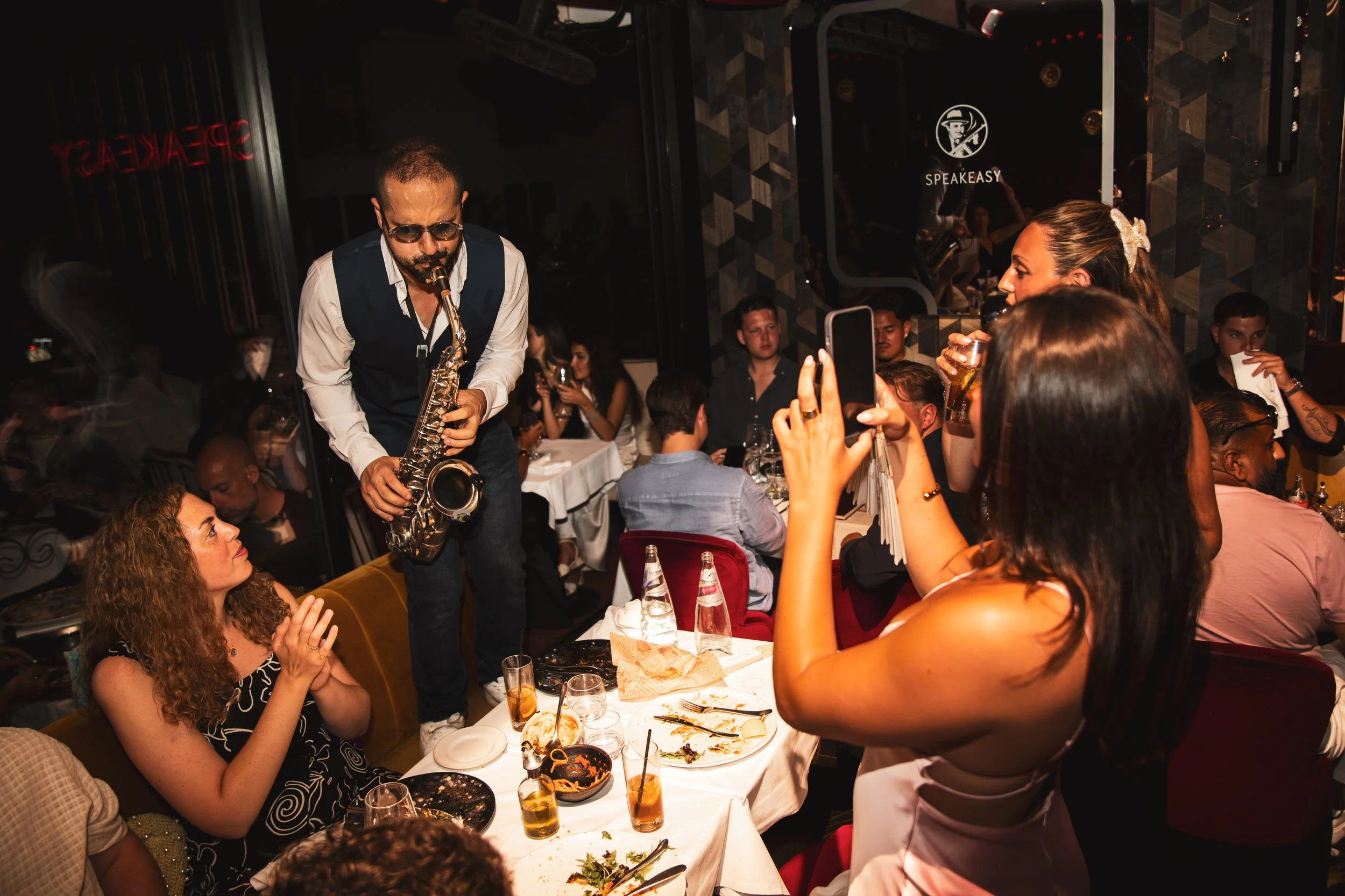 Saxophoniste jouant au milieu des tables pendant une soirée au Speakeasy