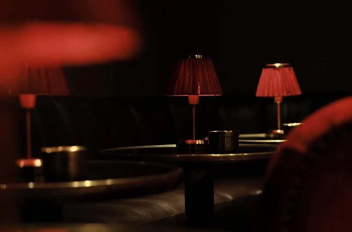 Trois lampes rouges sur une table dans une ambiance sombre, probablement dans un bar ou un restaurant.