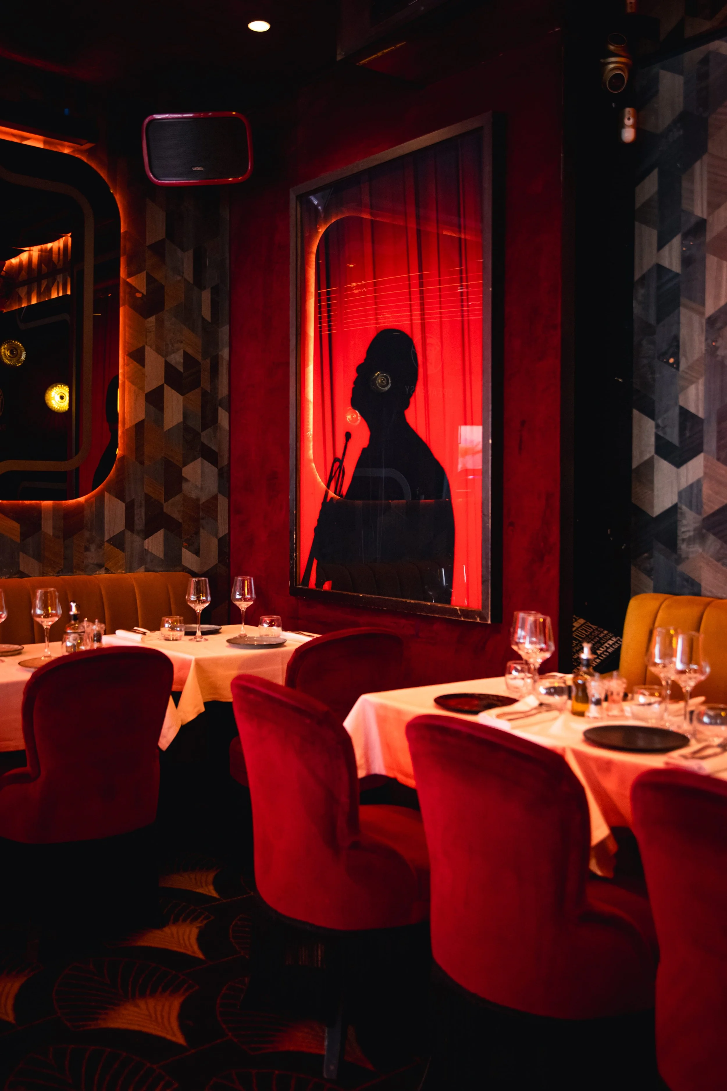 Salle du Speakeasy Cannes avec tables dressées, fauteuils rouges et lumière tamisée