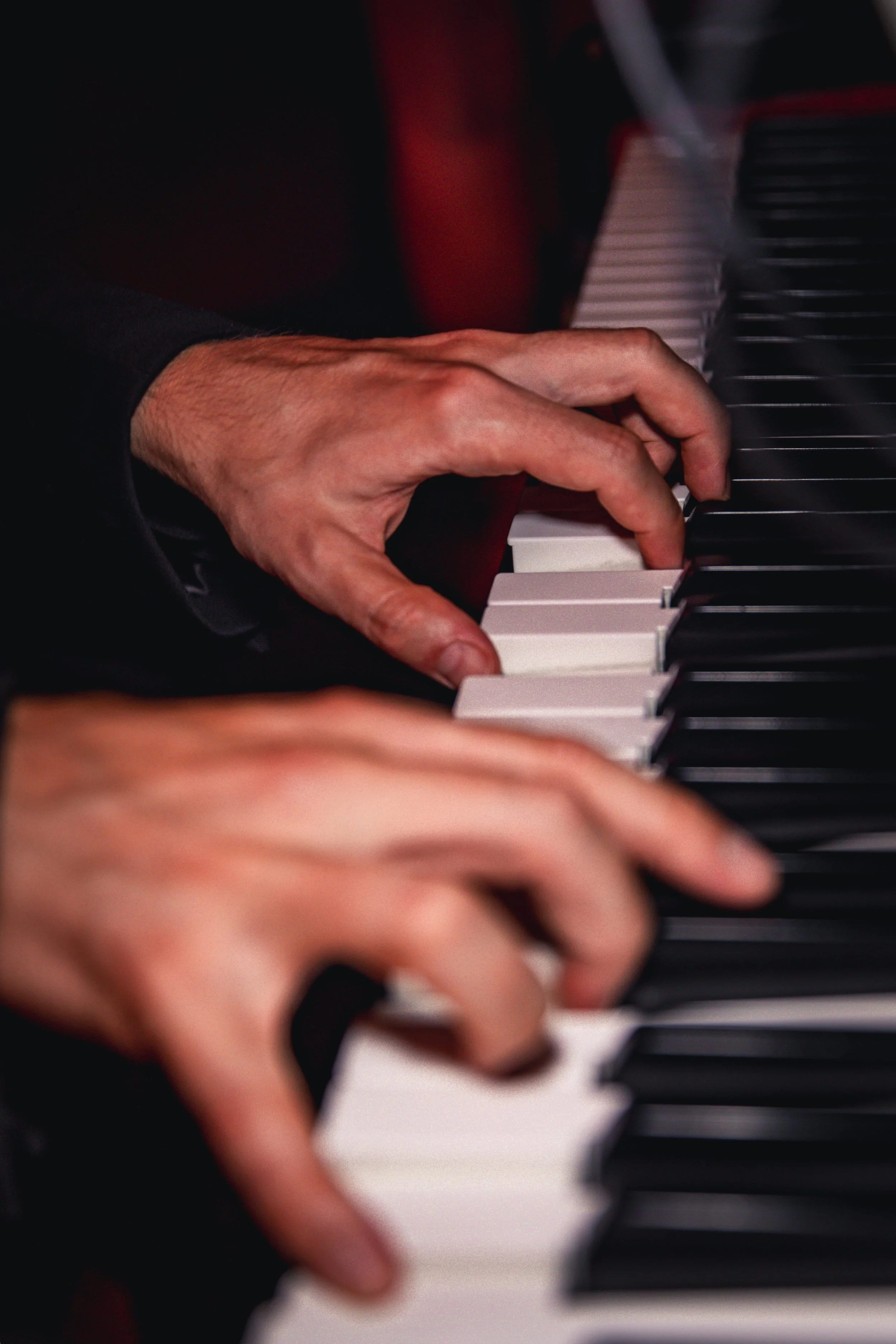 Une main d'adulte jouant du piano, avec des touches noires et blanches.