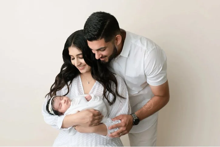 Newborn family photography in Modesto, CA capturing parents holding their new baby in a professional studio.